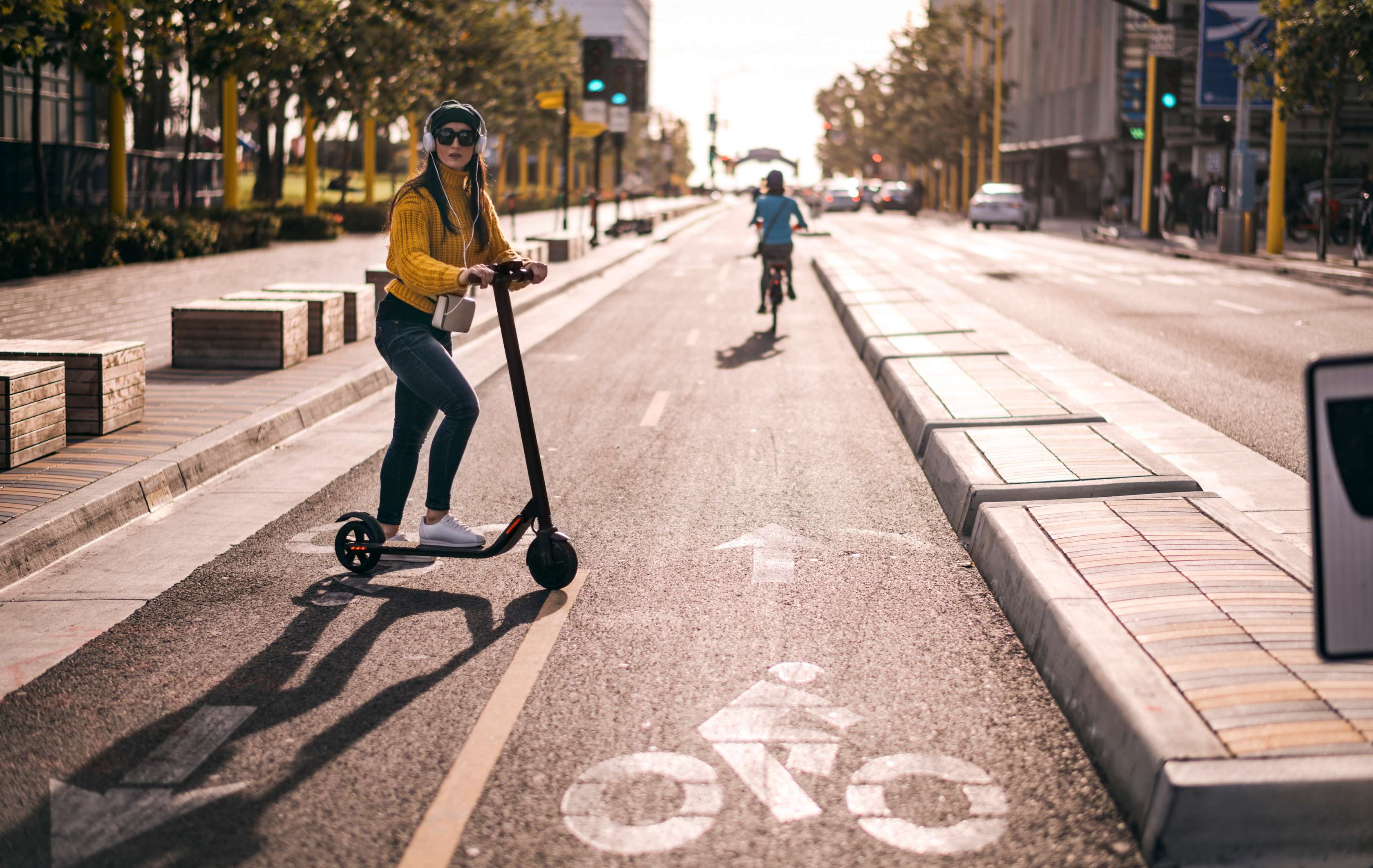 Allianz - E-Scooter Versicherung Angebot: E-Scooter Versicherung: Junge Frau überquert Straße mit Elektro-Tretroller.