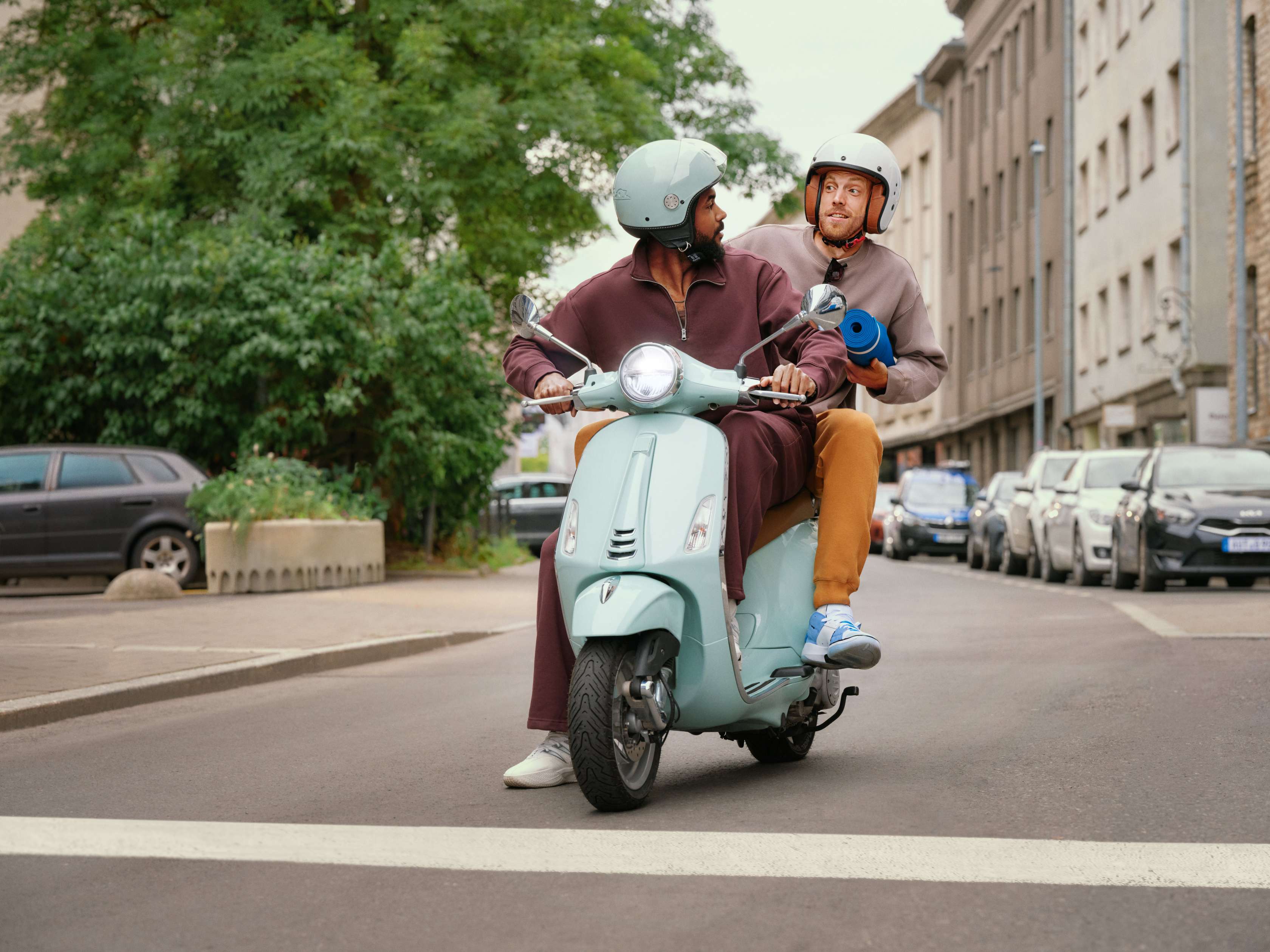 Allianz Mopedversicherung: Zwei junge Männer fahren mit einem Moped durch die Straße