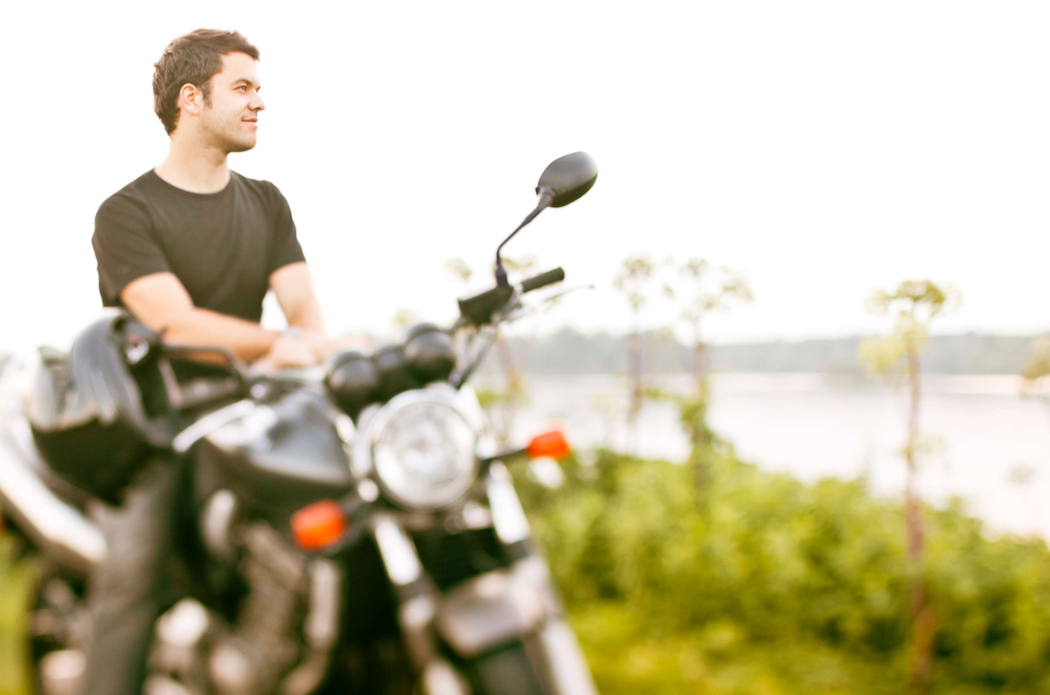 Mann sitzt bequem auf seinem Motorrad und schaut auf einen Fluss