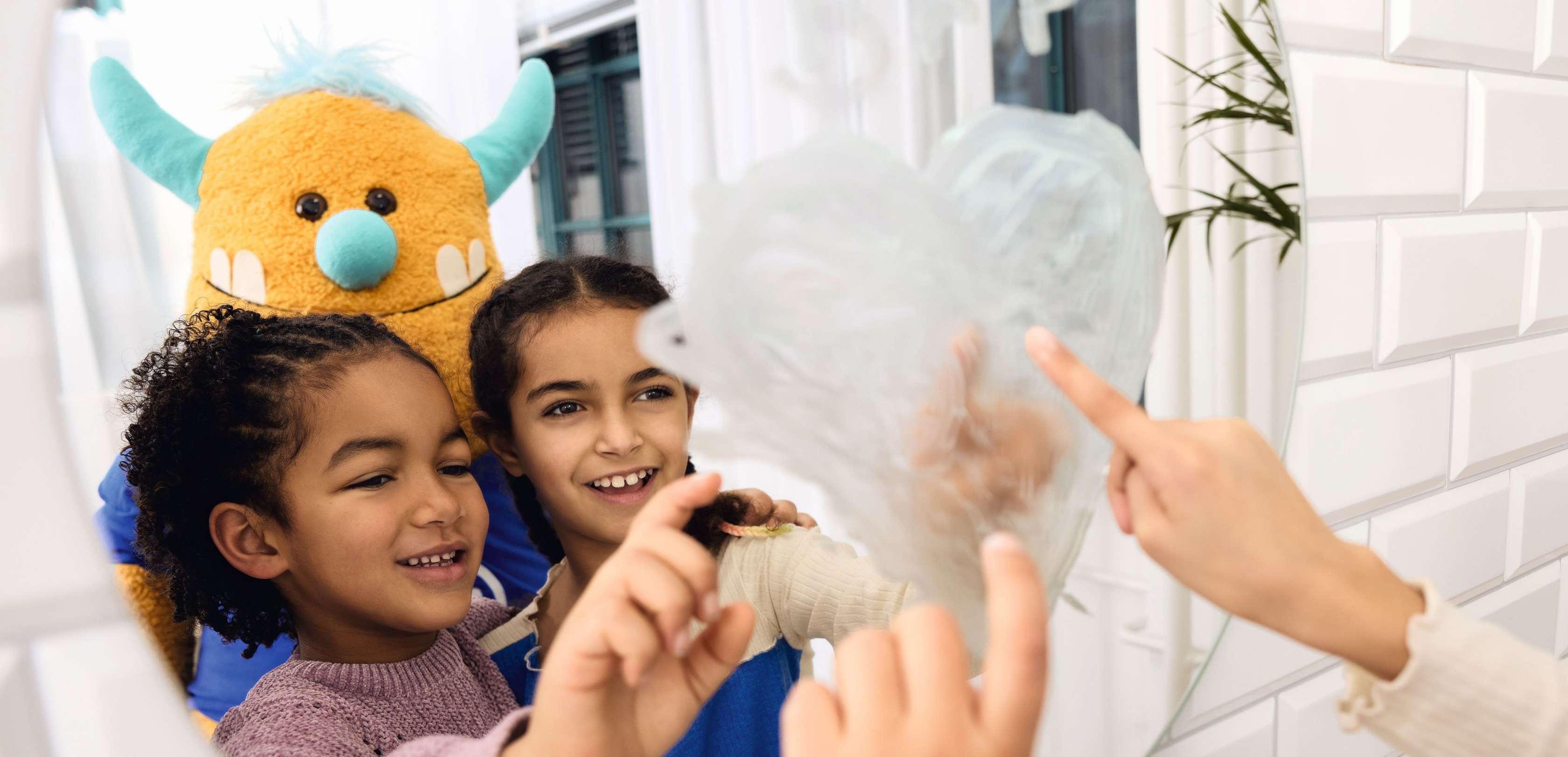 Allianz Kranken­zusatz­versicherungen für Kinder und Jugend­liche: Lachend Kinder stehen mit Kuscheltier im Badezimmer.