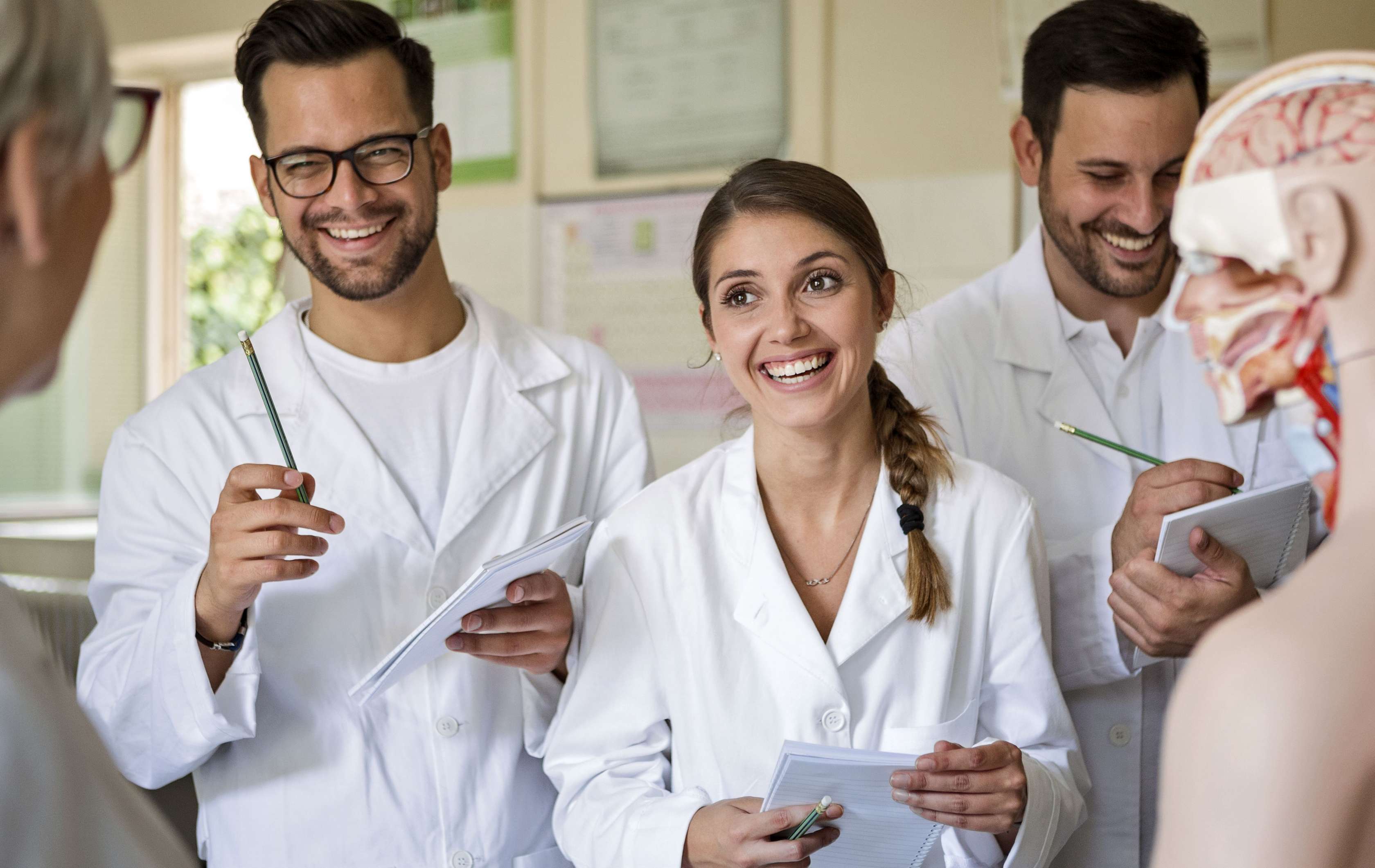 Allianz Private Krankenversicherung für Ärzte: Arzt mit Akte in der Hand lacht mit Patientin.