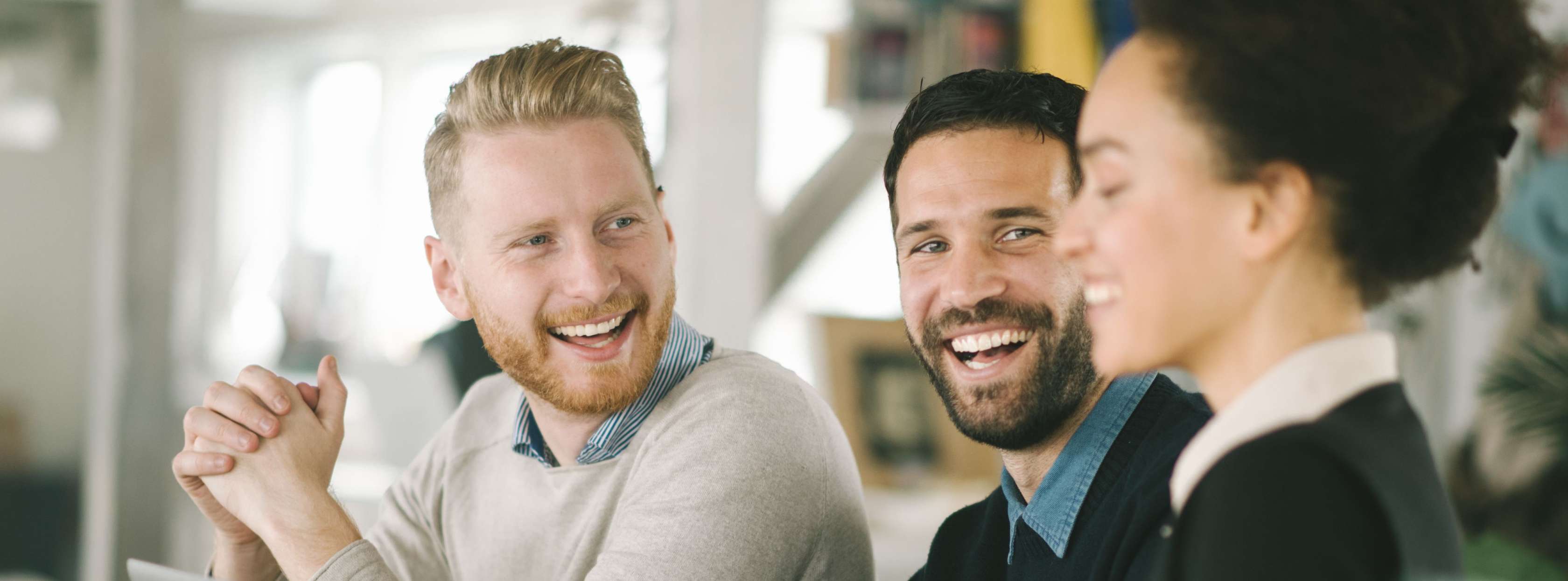 Allianz - Private Krankenversicherung - Angestellte: Zwei Männer und eine Frau lachend vor einem Laptop