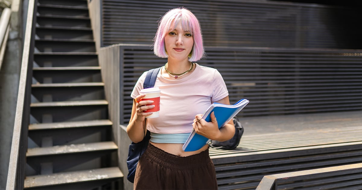 Allianz Optionstarif OptiFlexiMed die Eintrittskarte für die private Krankenversicherung. Eine Studentin steht vor einer Treppe und blickt in die Kamera.