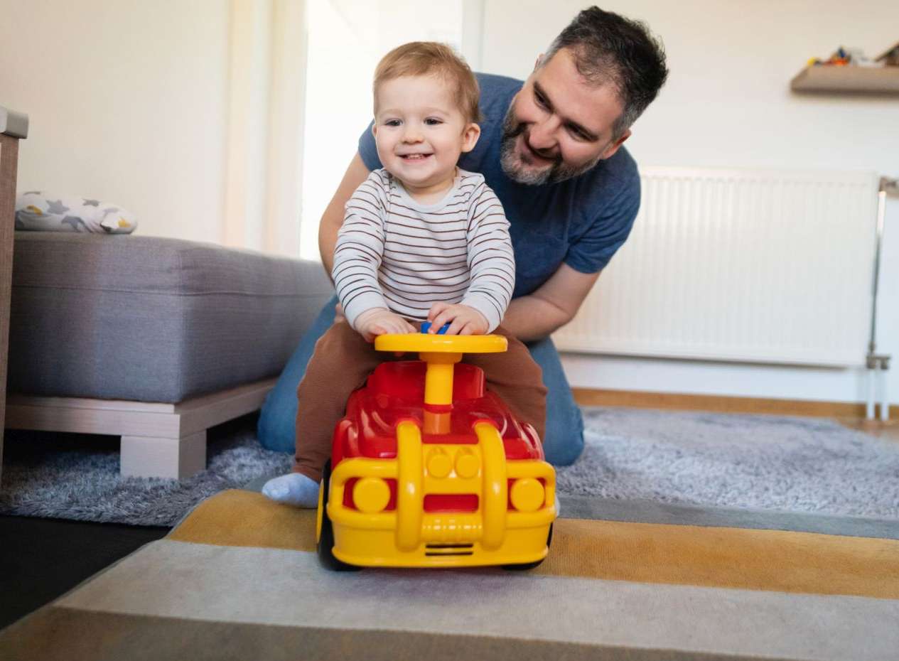 Allianz Versicherungen für Kinder: Vater und Sohn spielen mit einem Spielzeugauto