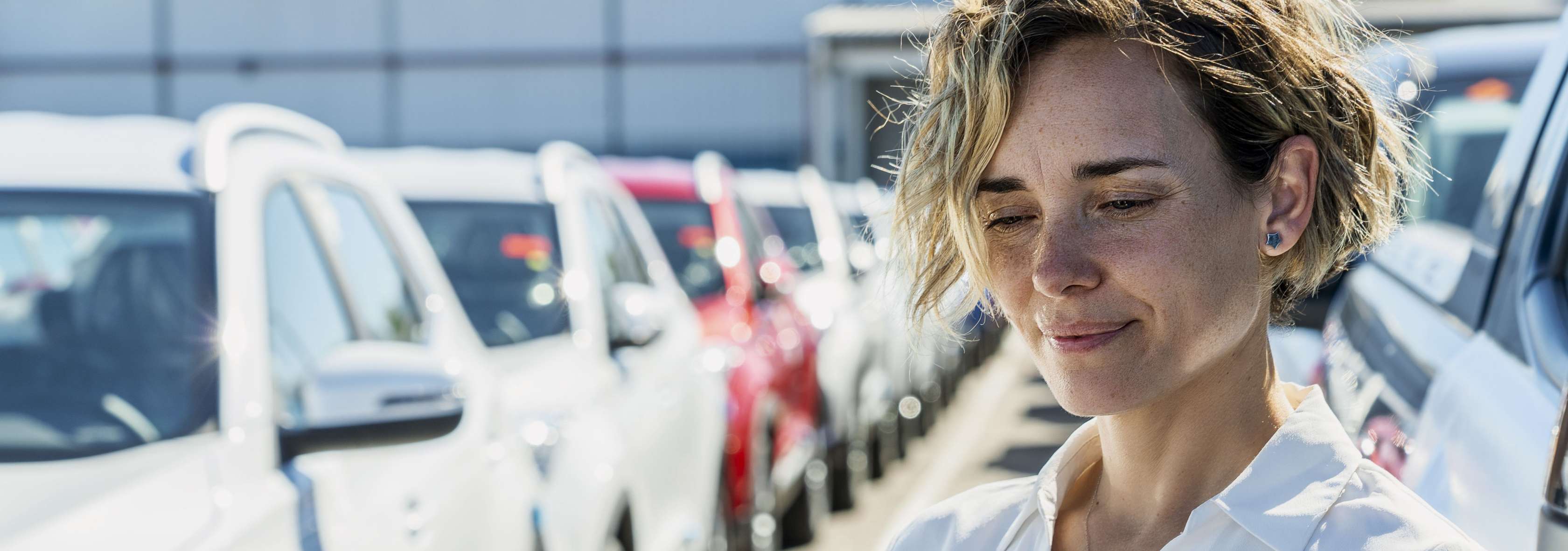 Allianz - Flottenversicherung: Eine Geschäftsfrau steht mit einem Ipad zwischen mehreren Geschäftswagen.