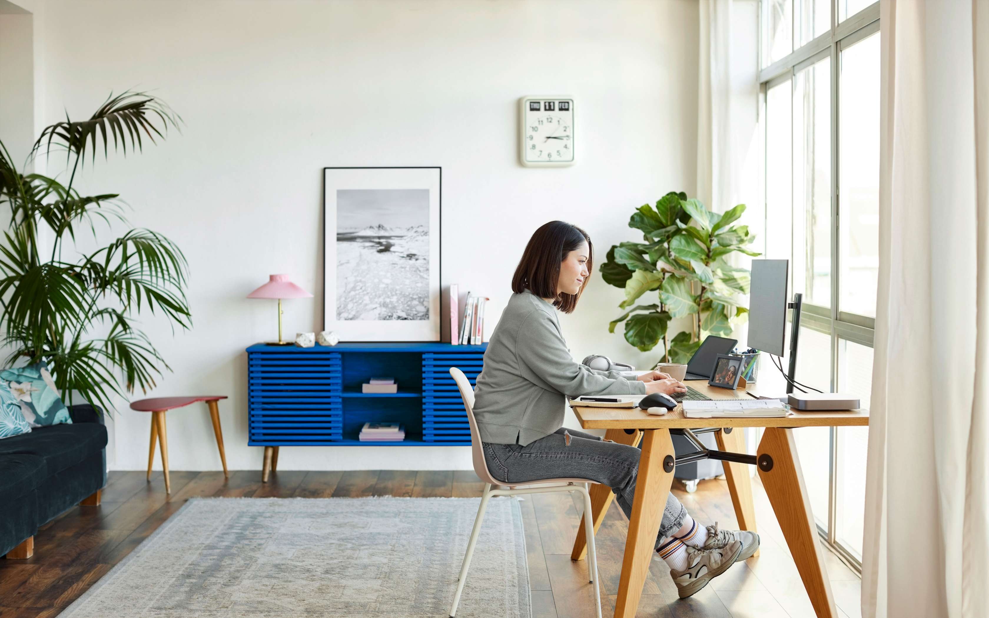 Junge Frau sitzt zuhause am Schreibtisch an einem Computer