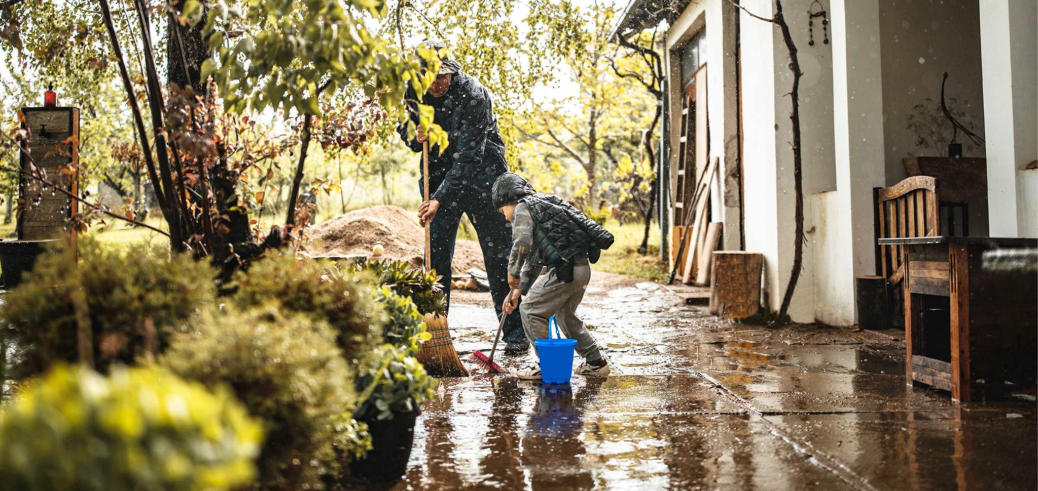 Elementarversicherung: Vater und Sohn kehren vor Haus  im Regen