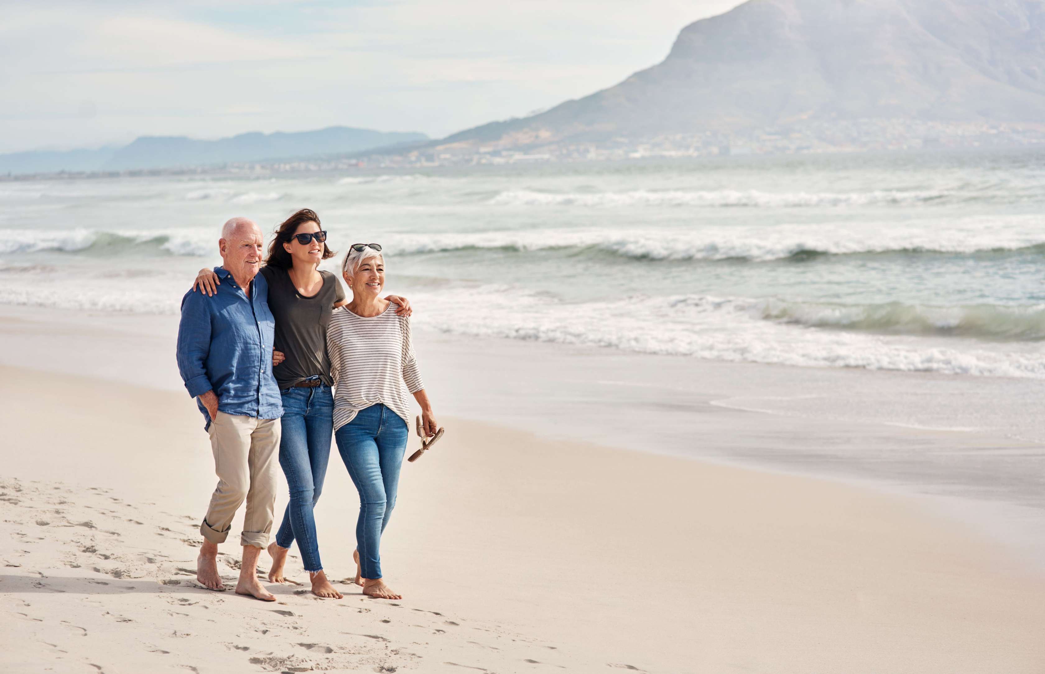 Ehepaar geht mit erwachsener Tochter am Strand spazieren