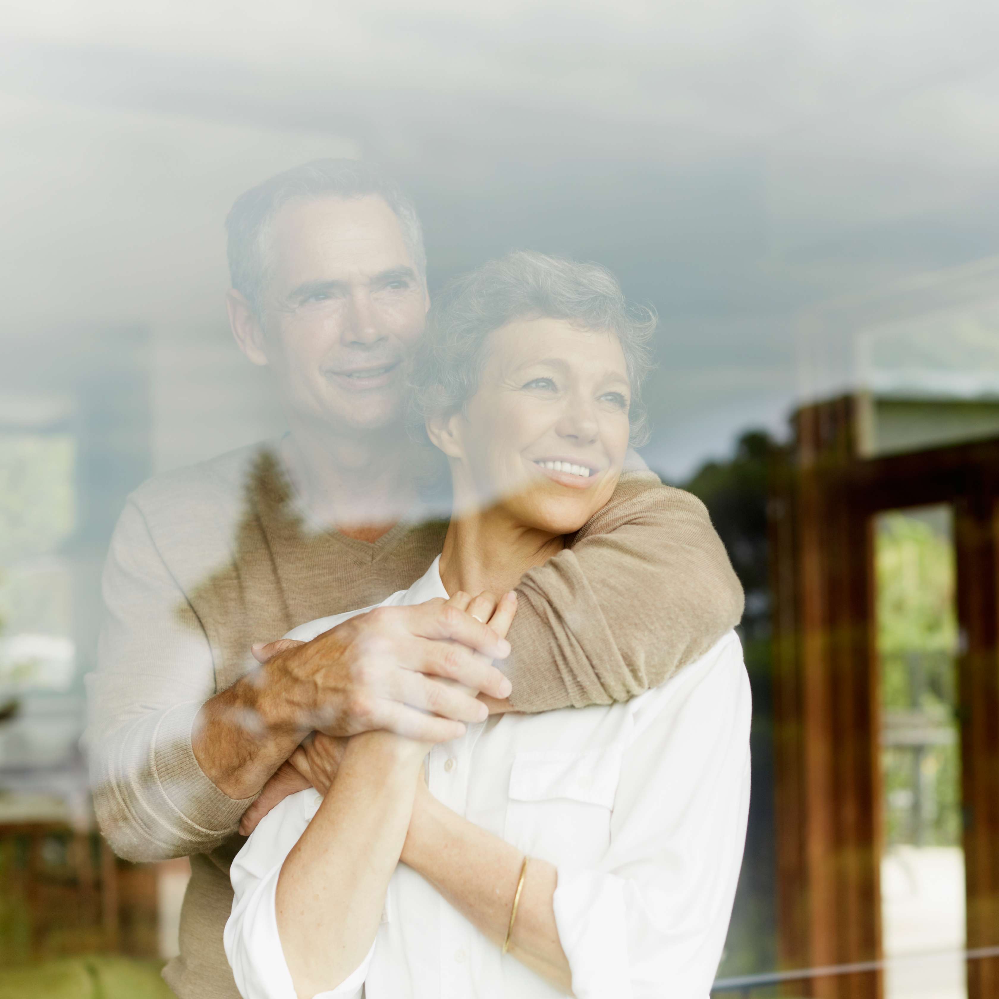 Allianz - Private Rentenversicherung: Älteres Ehepaar blickt zufrieden durch eine große Glasscheibe