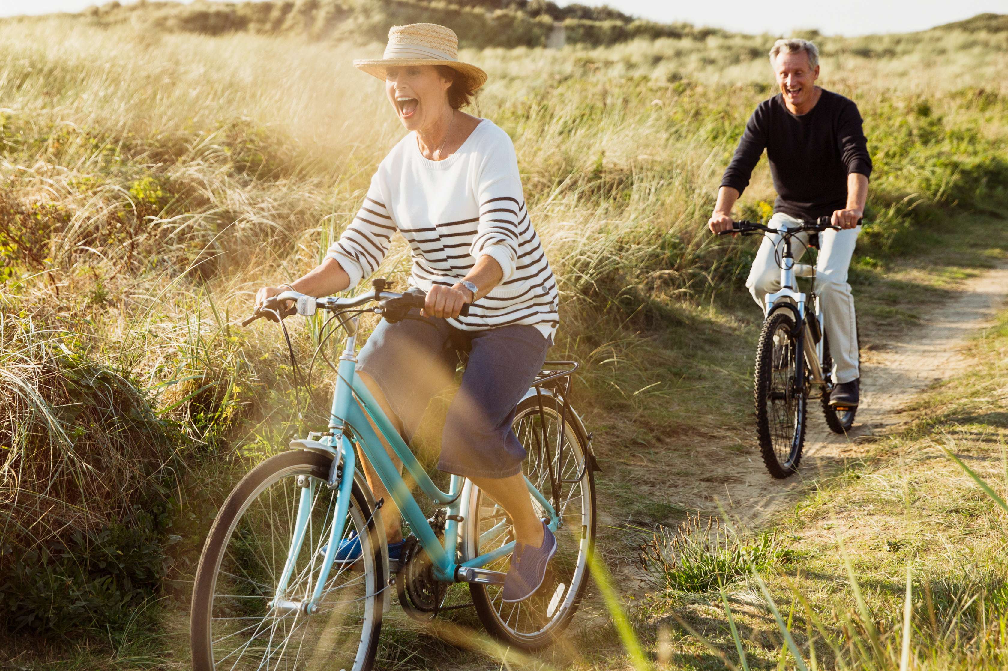 Allianz Private Rentenversicherung: Ein Mann und eine Frau fahren auf Fahrrädern durch die Dünen