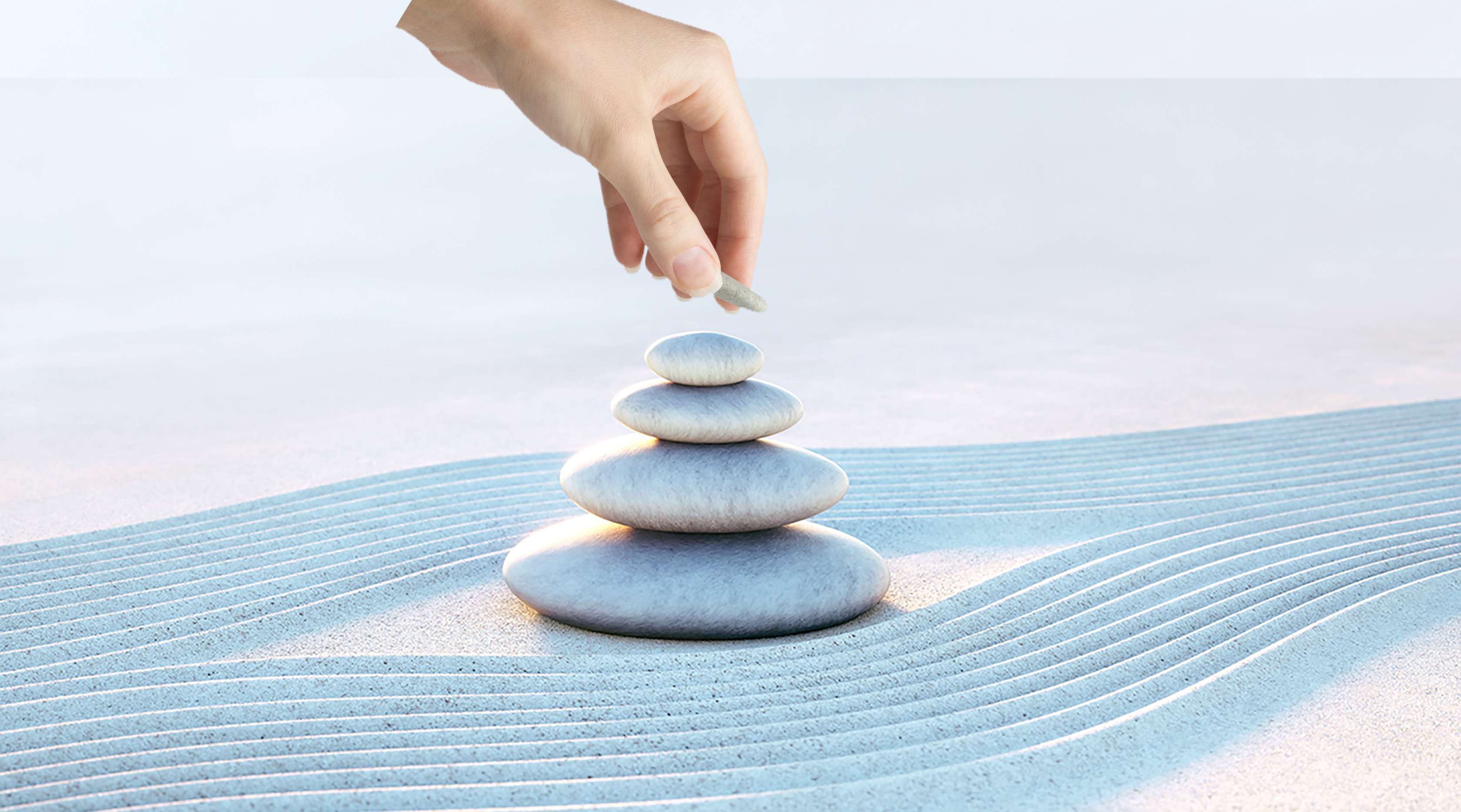 SchatzBrief: Steinstapel am Strand, Finger einer Frau legen einen Stein auf den Stapel  