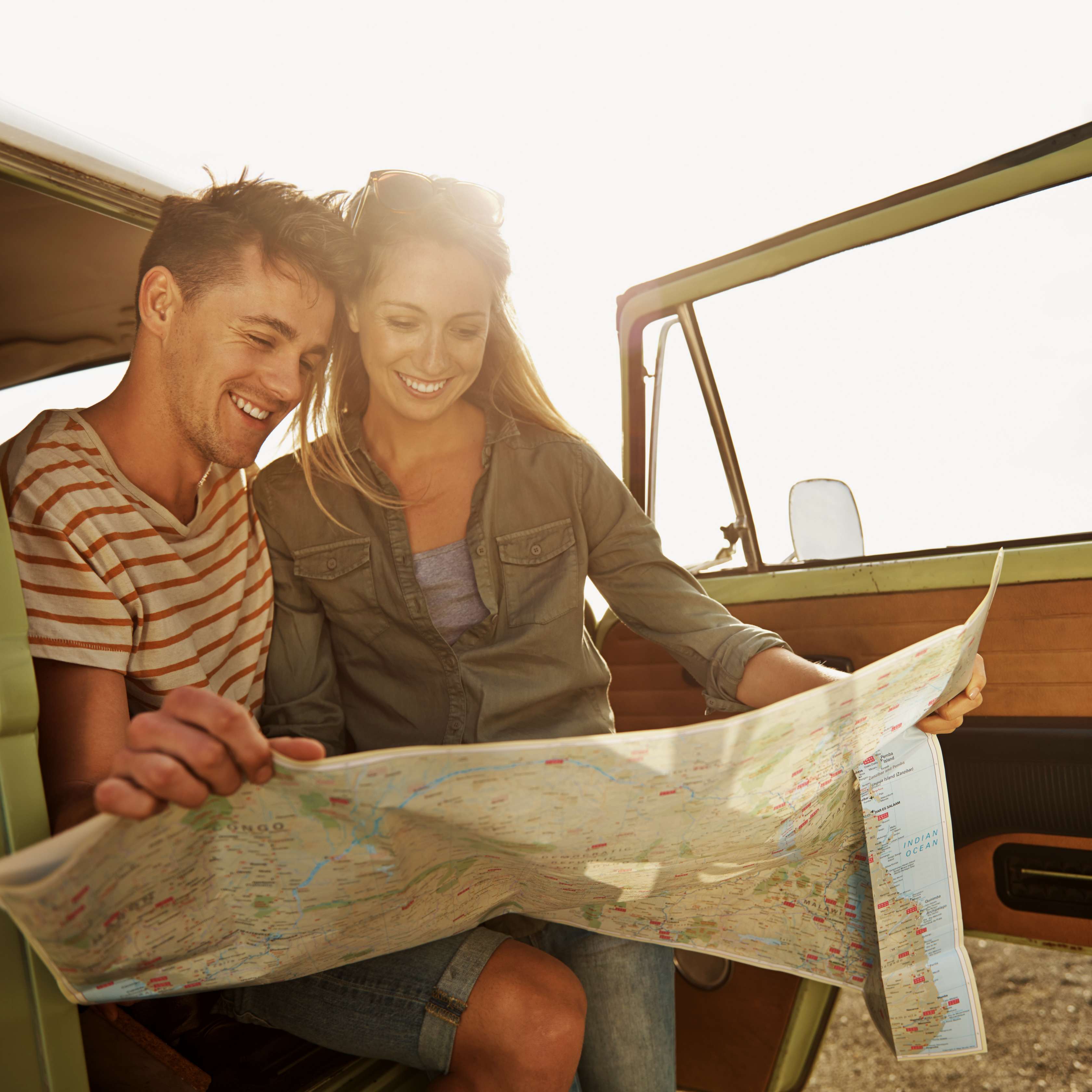 Junges Paar mit einer Landkarte in einem Jeep auf Reisen