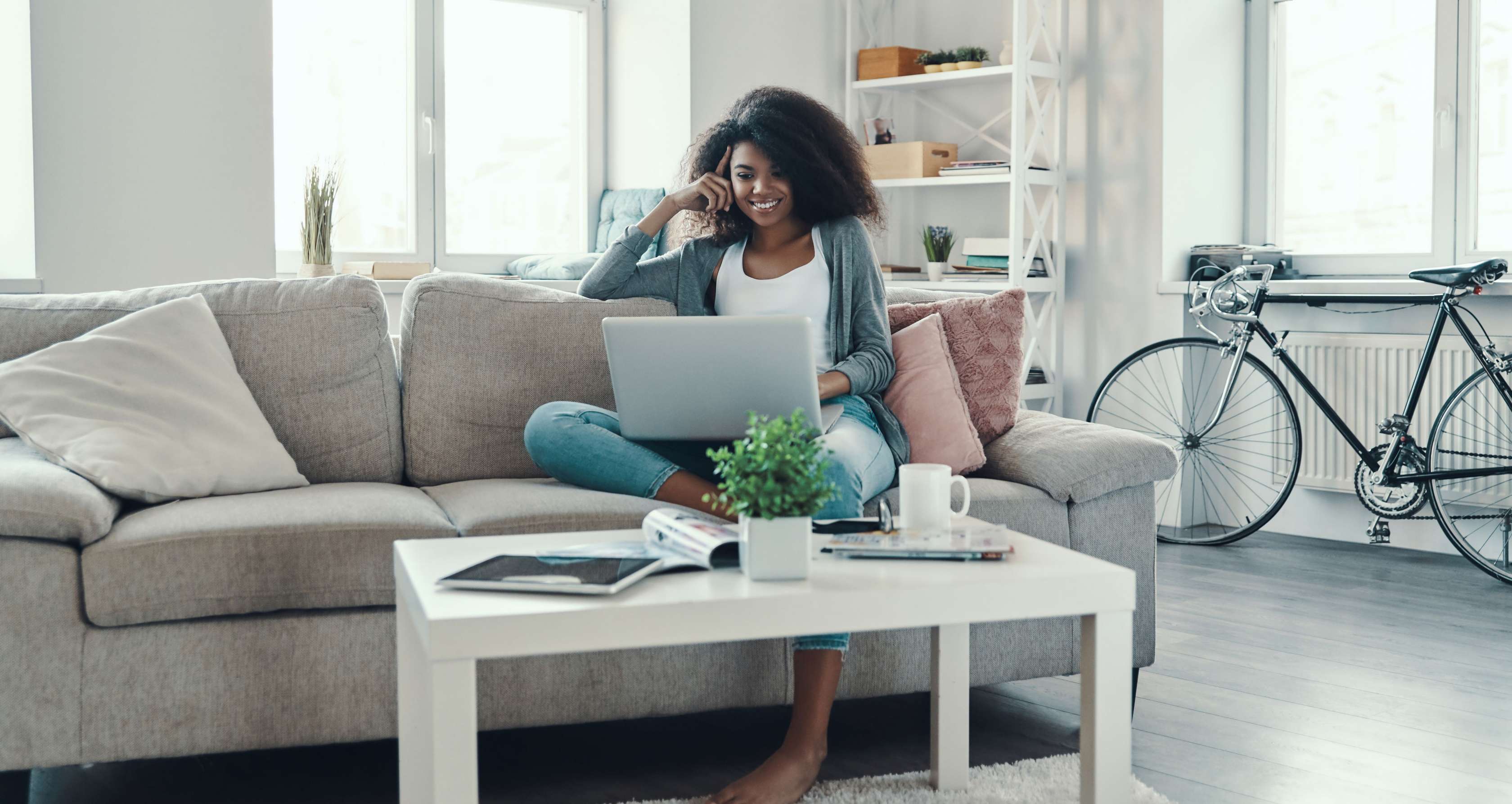 Allianz Online Events: Eine Frau sitzt auf einem Sofa und schaut in ihren Laptop.