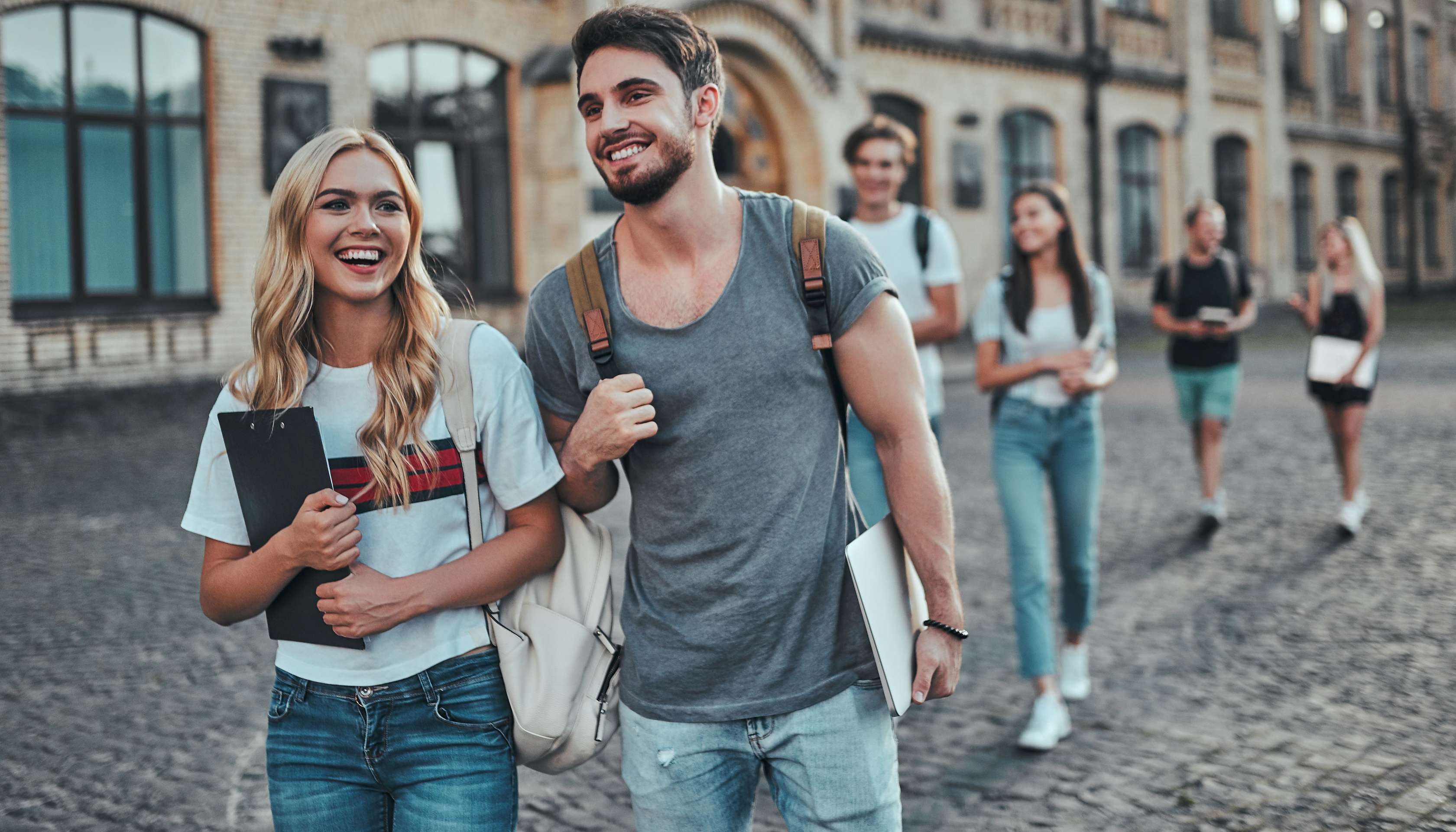 Allianz - Gratis Reisekrankenversicherung: Junger Mann und junge Frau laufend lachend auf einem Platz