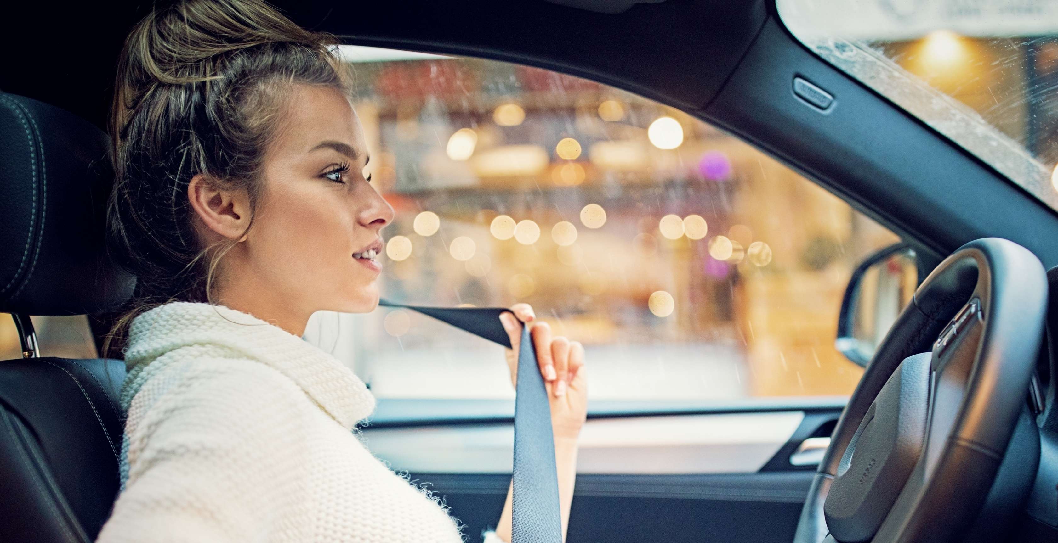 Allianz Verkehrsrechtsschutzversicherung: Junge Frau sitzt im Auto und legt ihren Sicherheitsgurt an.