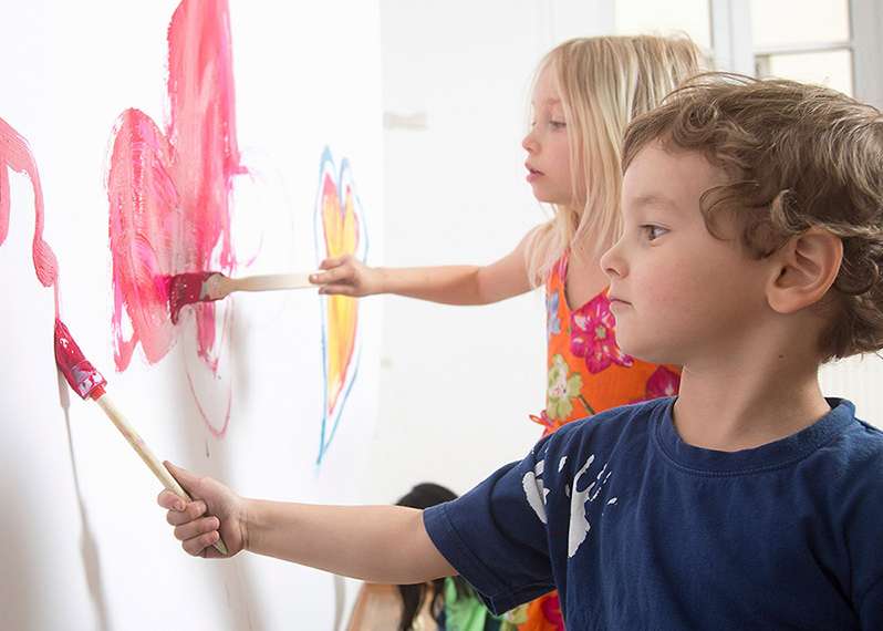Zwei Kinder malen die Zimmerwand bunt an