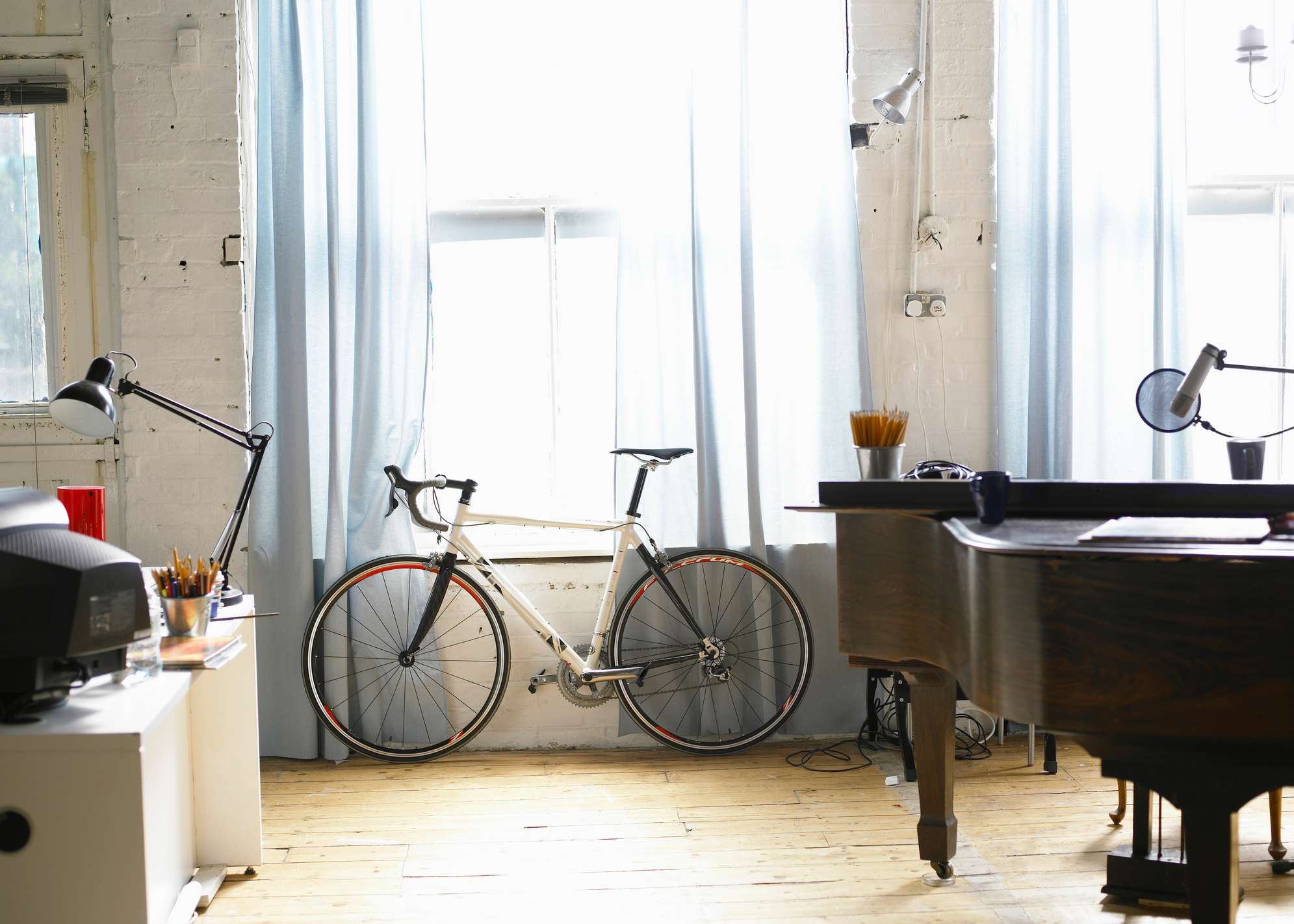 Innenraum einer Wohnung mit Fahrrad, Flügel und Schreibtisch