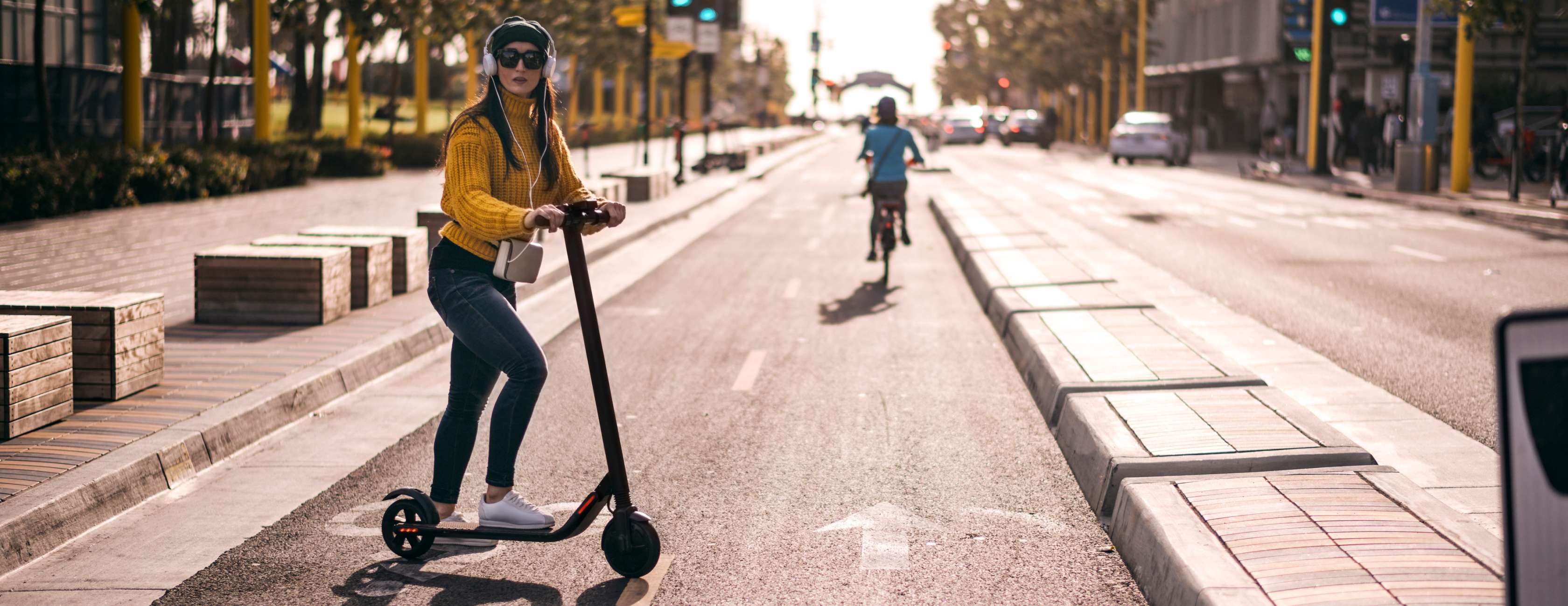 E-Scooter Versicherung: Junge Frau überquert Straße mit Elektro-Tretroller