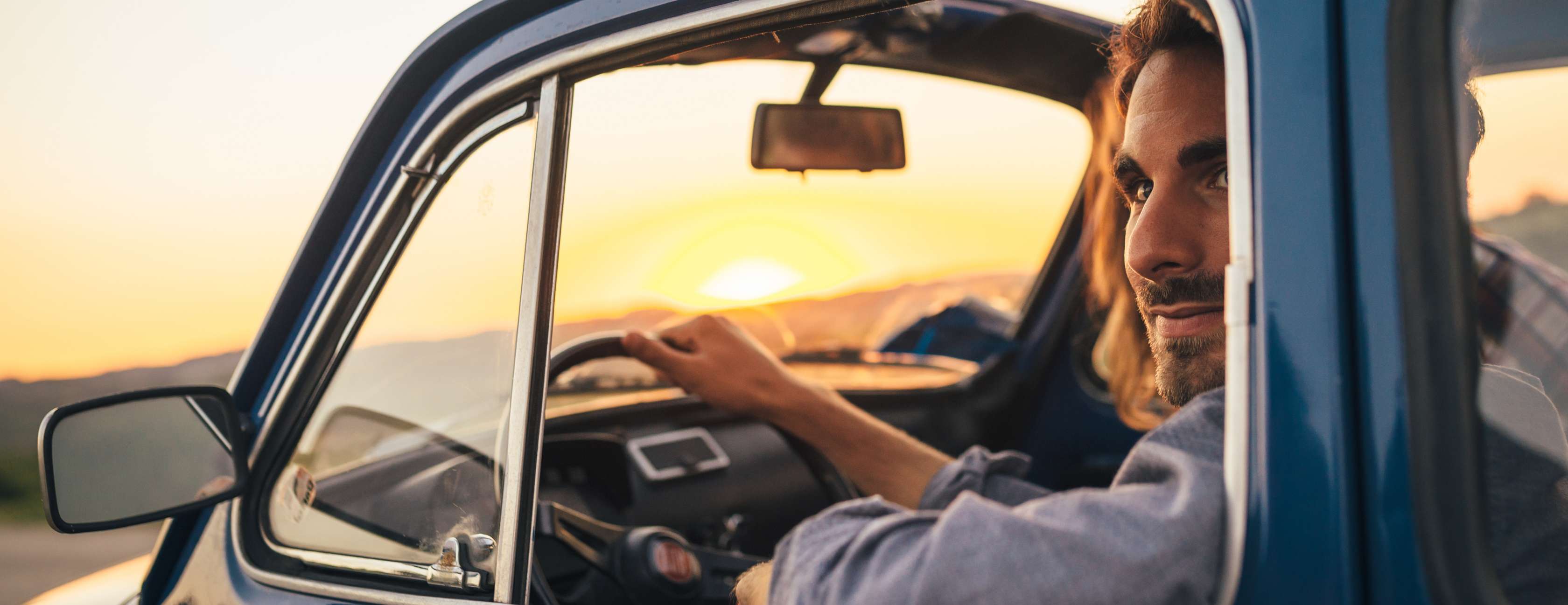  Mann sitzt bei Sonnenuntergang am Steuer seines Autos