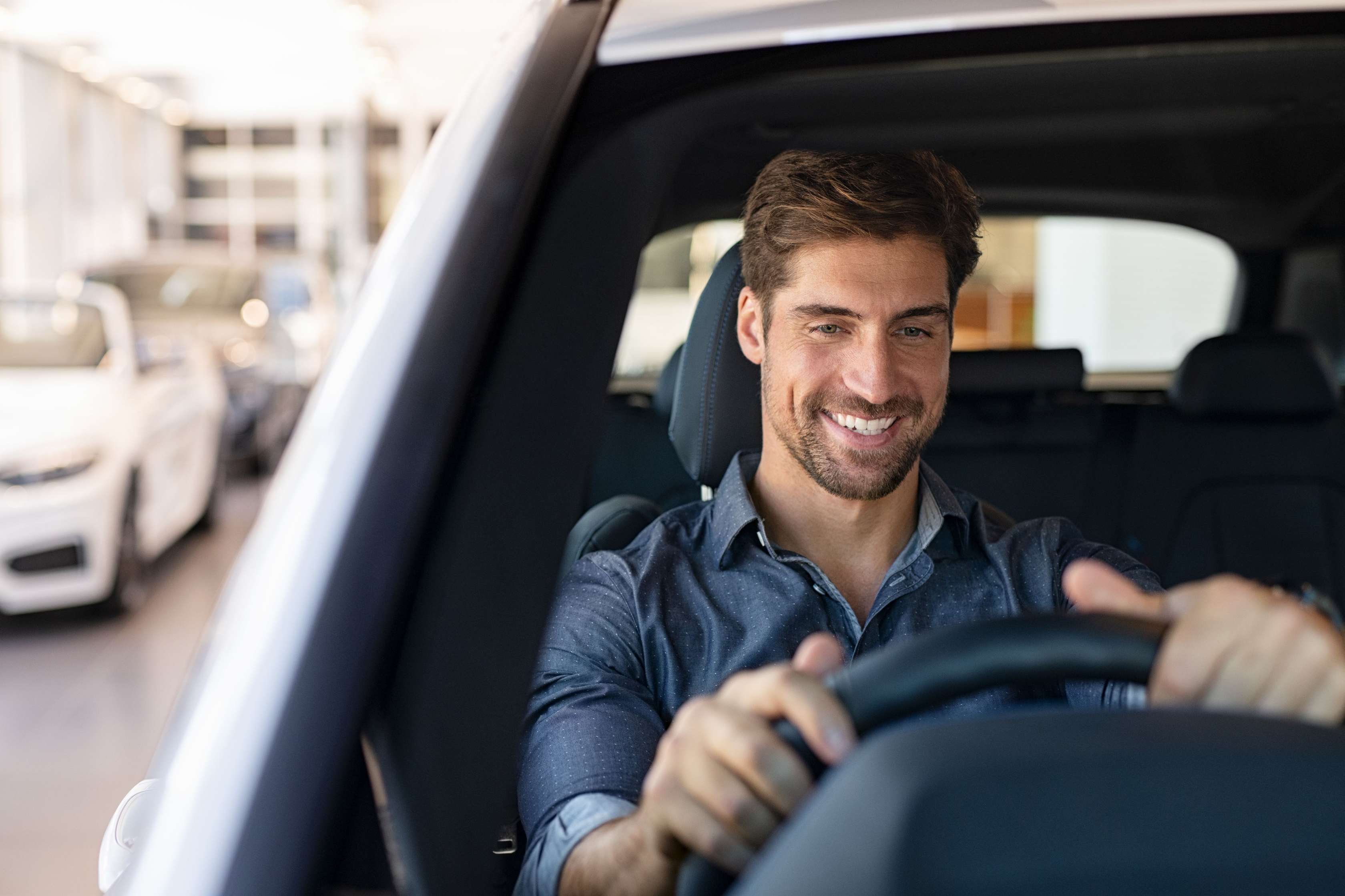 25 kmh Auto ohne Führerschein: Mann sitzt lächelnd am Steuer eines Pkw