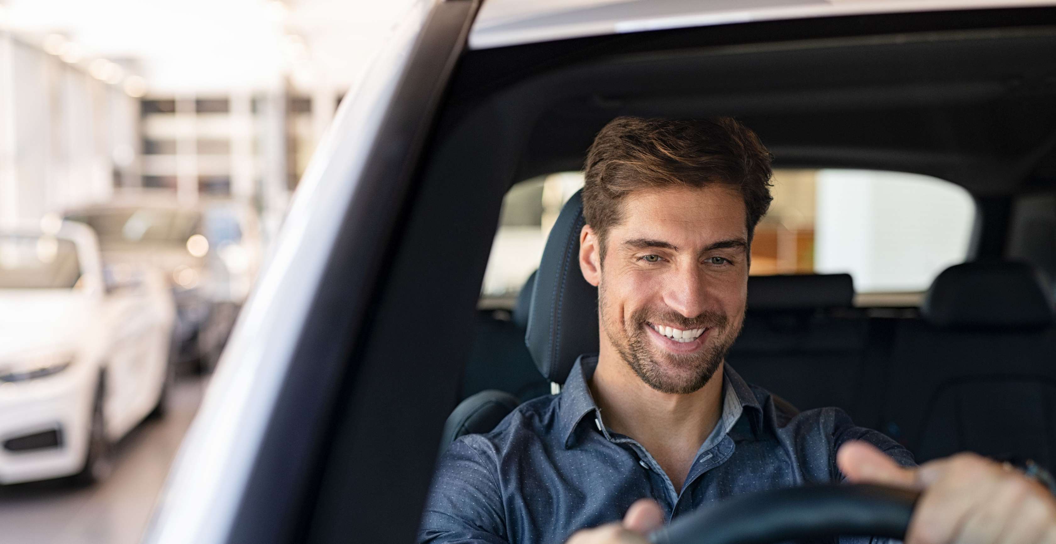 25 kmh Auto ohne Führerschein: Mann sitzt lächelnd am Steuer eines Pkw