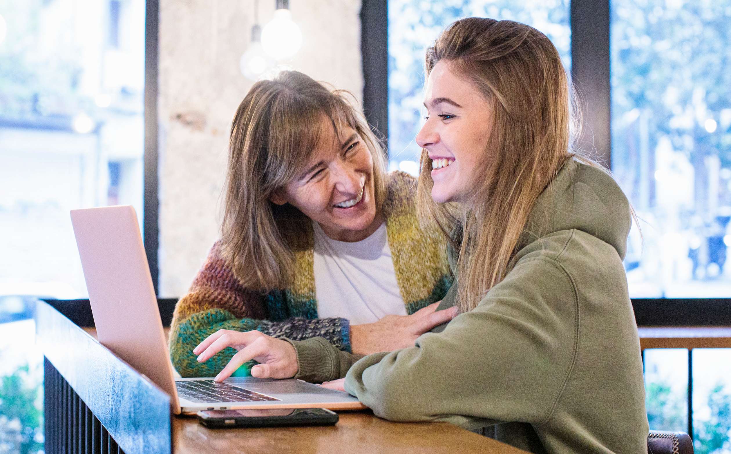 Autoversicherung über Eltern: Mutter und Tochter sehen zusammen in ein Laptop