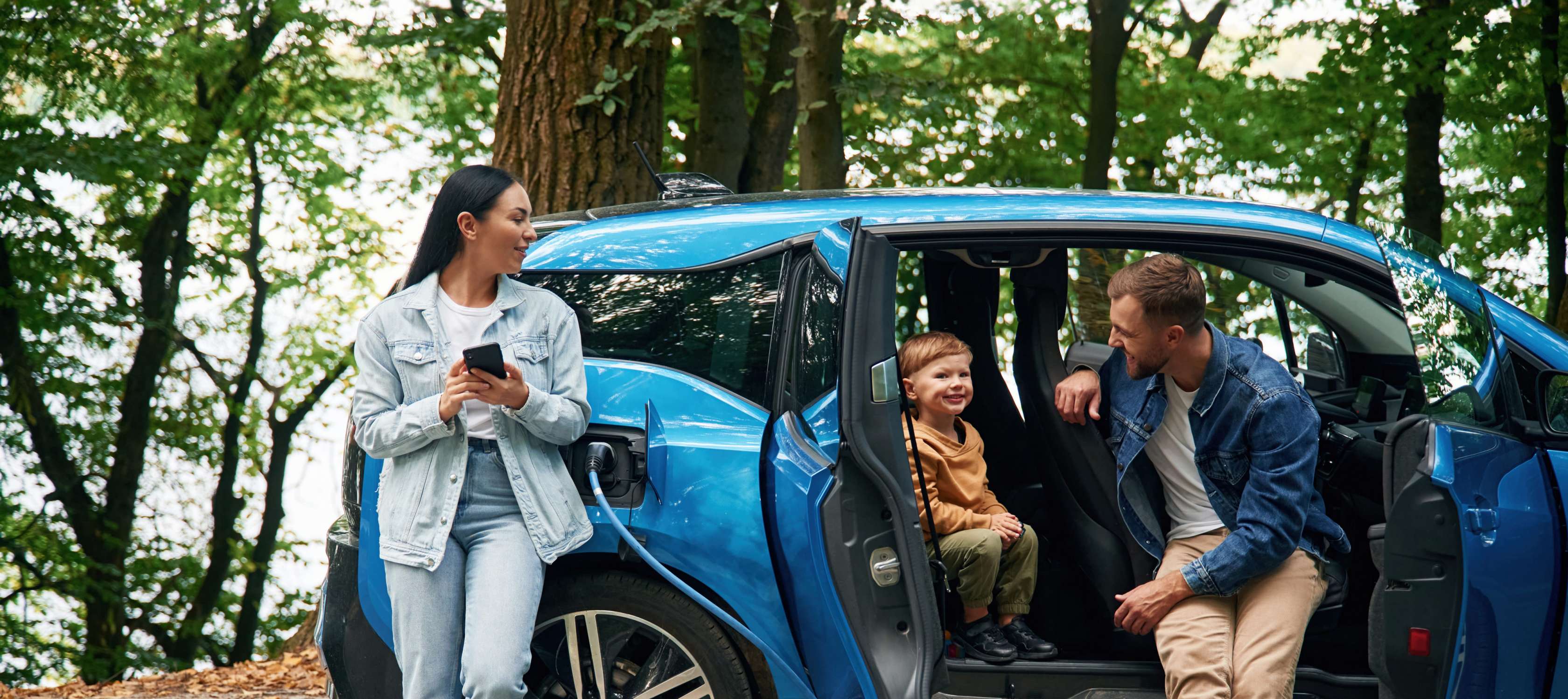 E-Autos fürFamilien: Eine Familie lädt ihr Elektroauto, auf der Rückbank sitzt ein Kleinkind