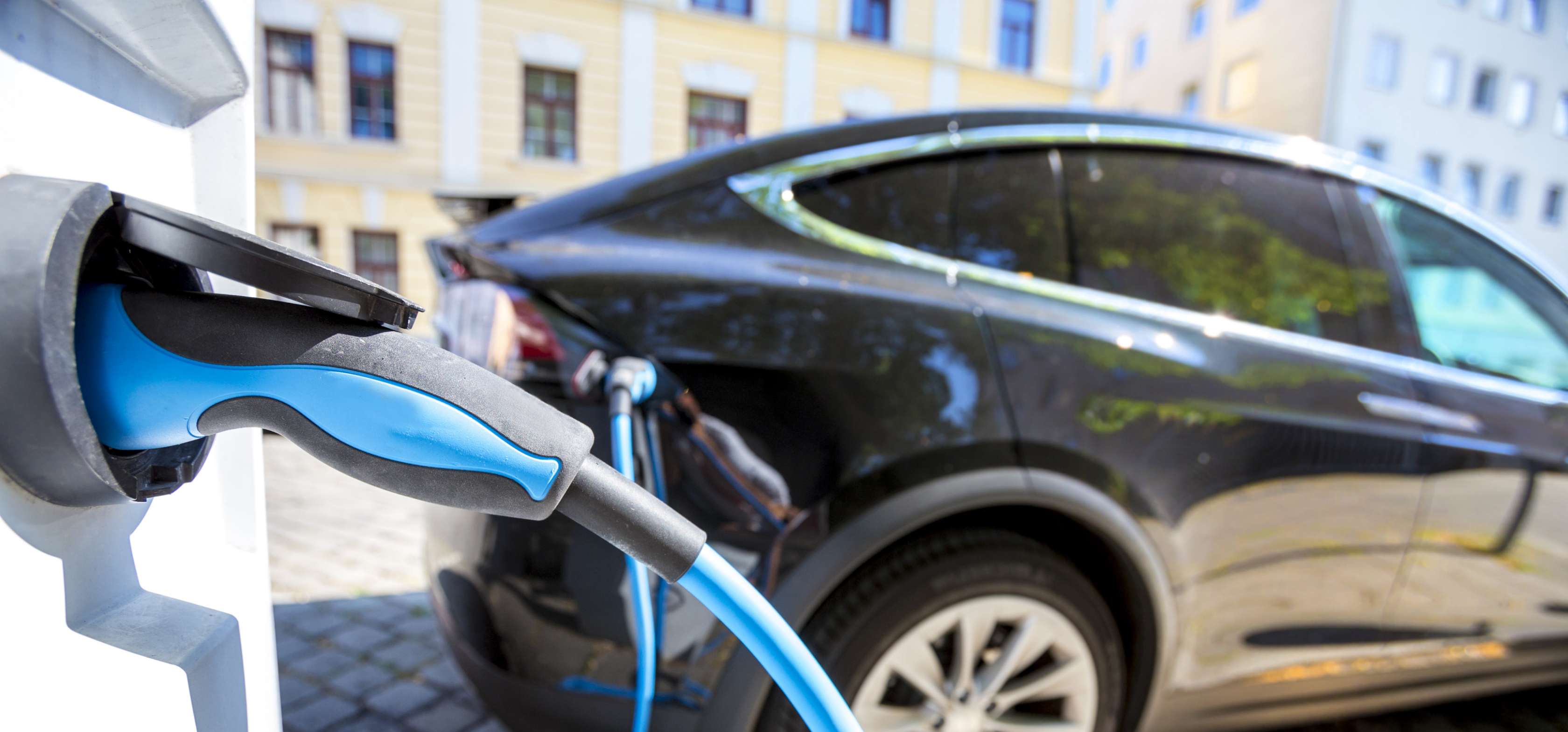 E Auto Förderung: Elektroaouto ist per Ladekabel an Ladesäule angeschlossen