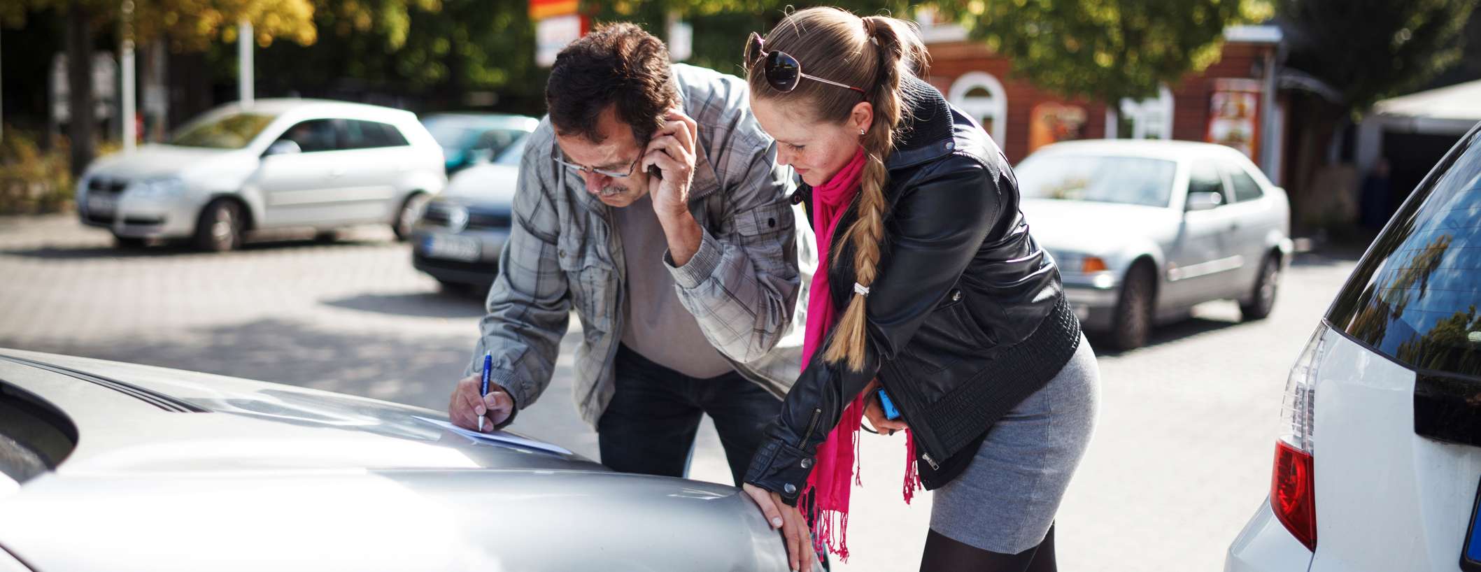 Allianz - Europäischer Unfallbericht: Frau füllt gemeinsam mit Mann, der telefoniert, an Unfallstelle ein Formular aus