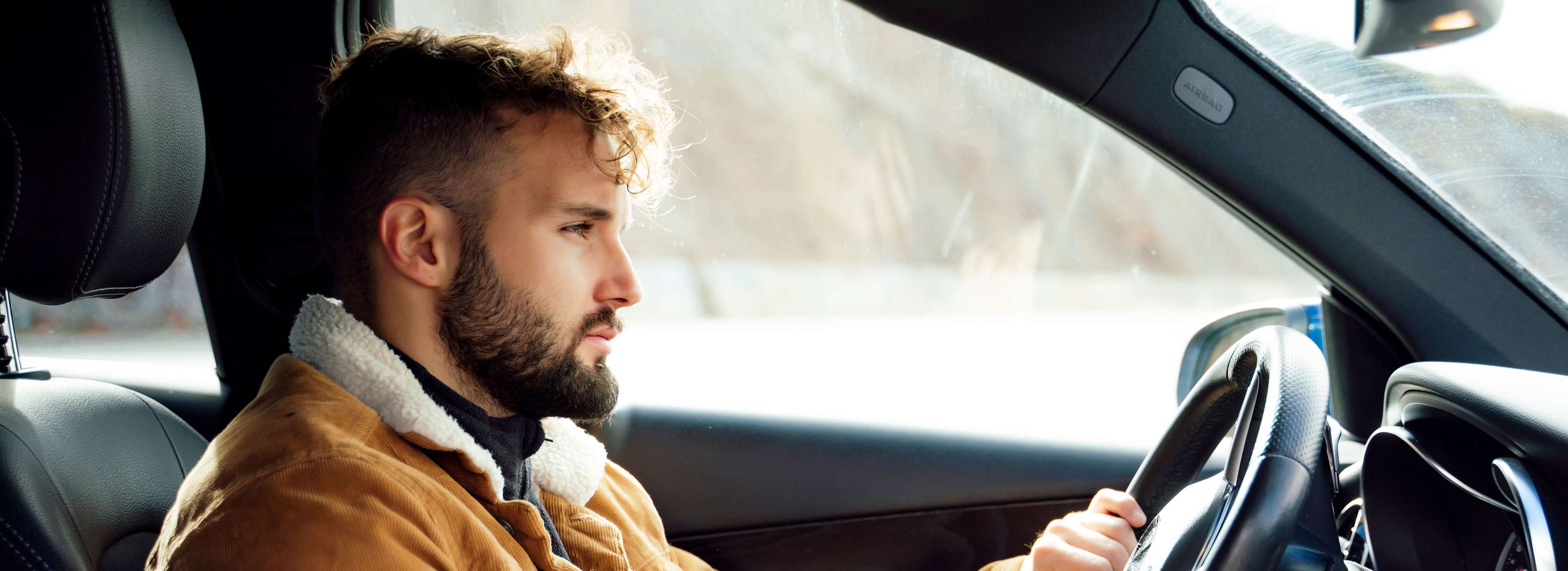 Kfz-Haftpflichtversicherung: Mann sitzt im Auto und schaut nach vorne