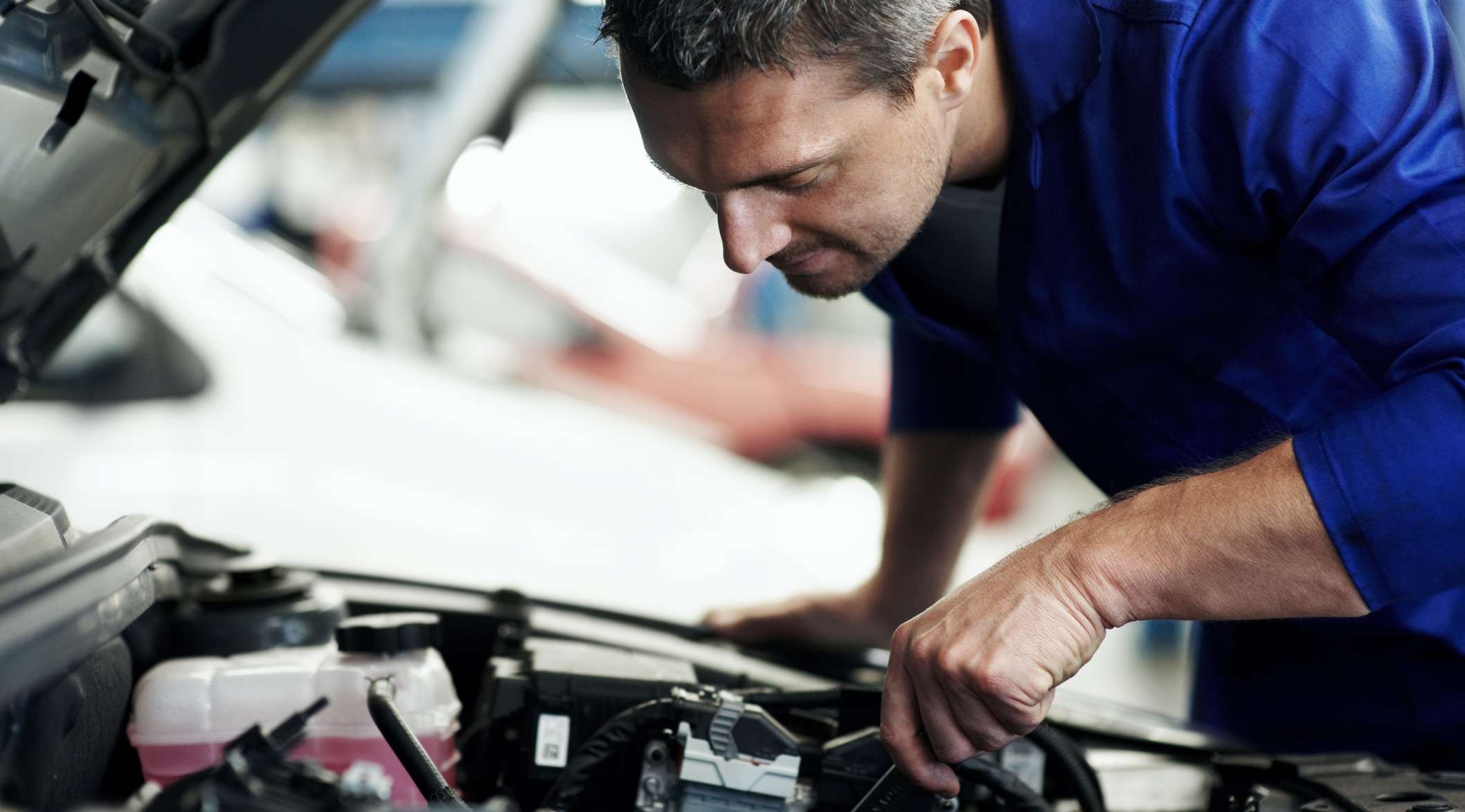 Automechaniker prüft Motor eines Pkw in Werkstatt