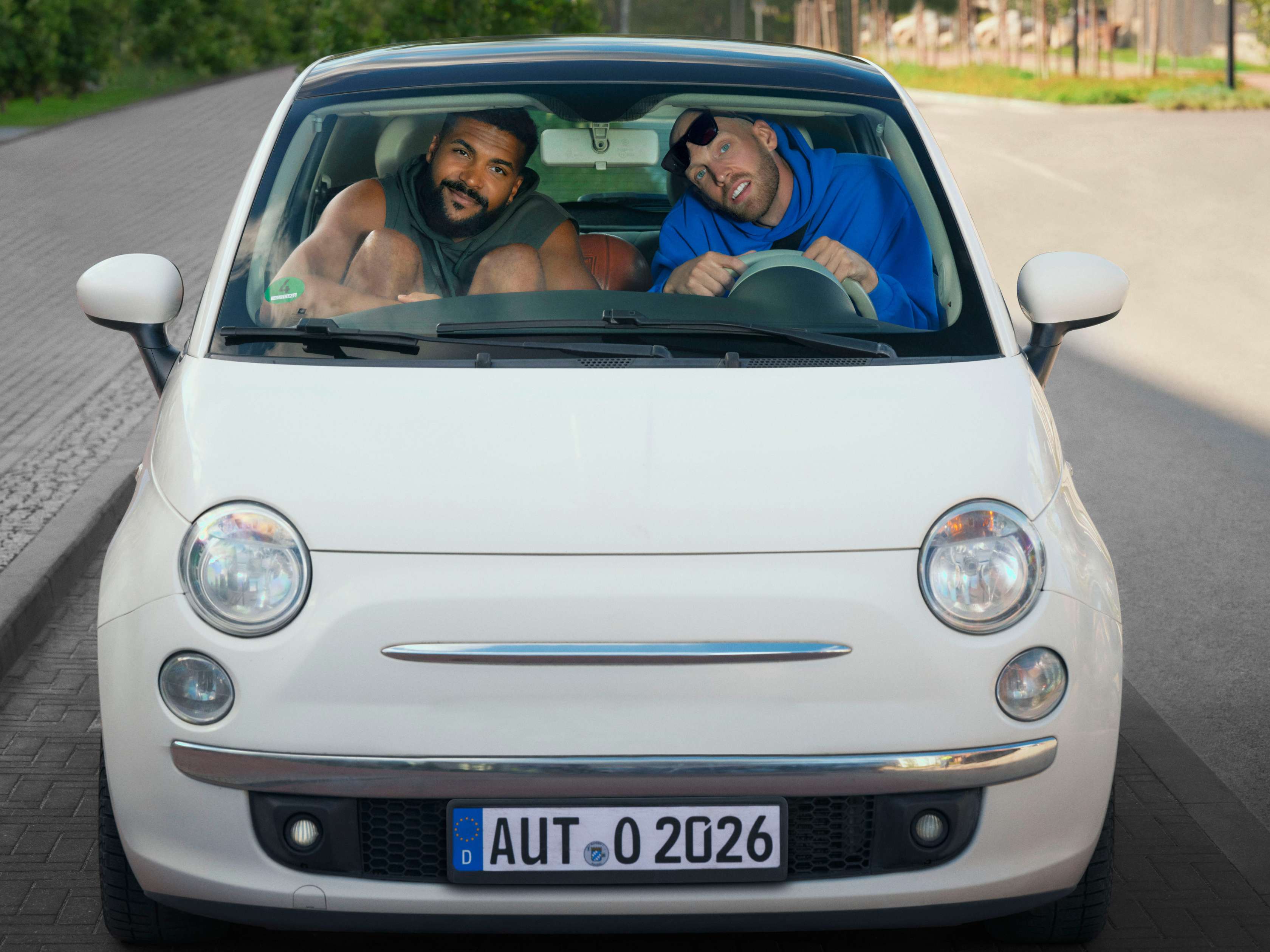 Schutzbrief: zwei sehr große Basketballprofis sitzen ein einem sehr kleinen Auto