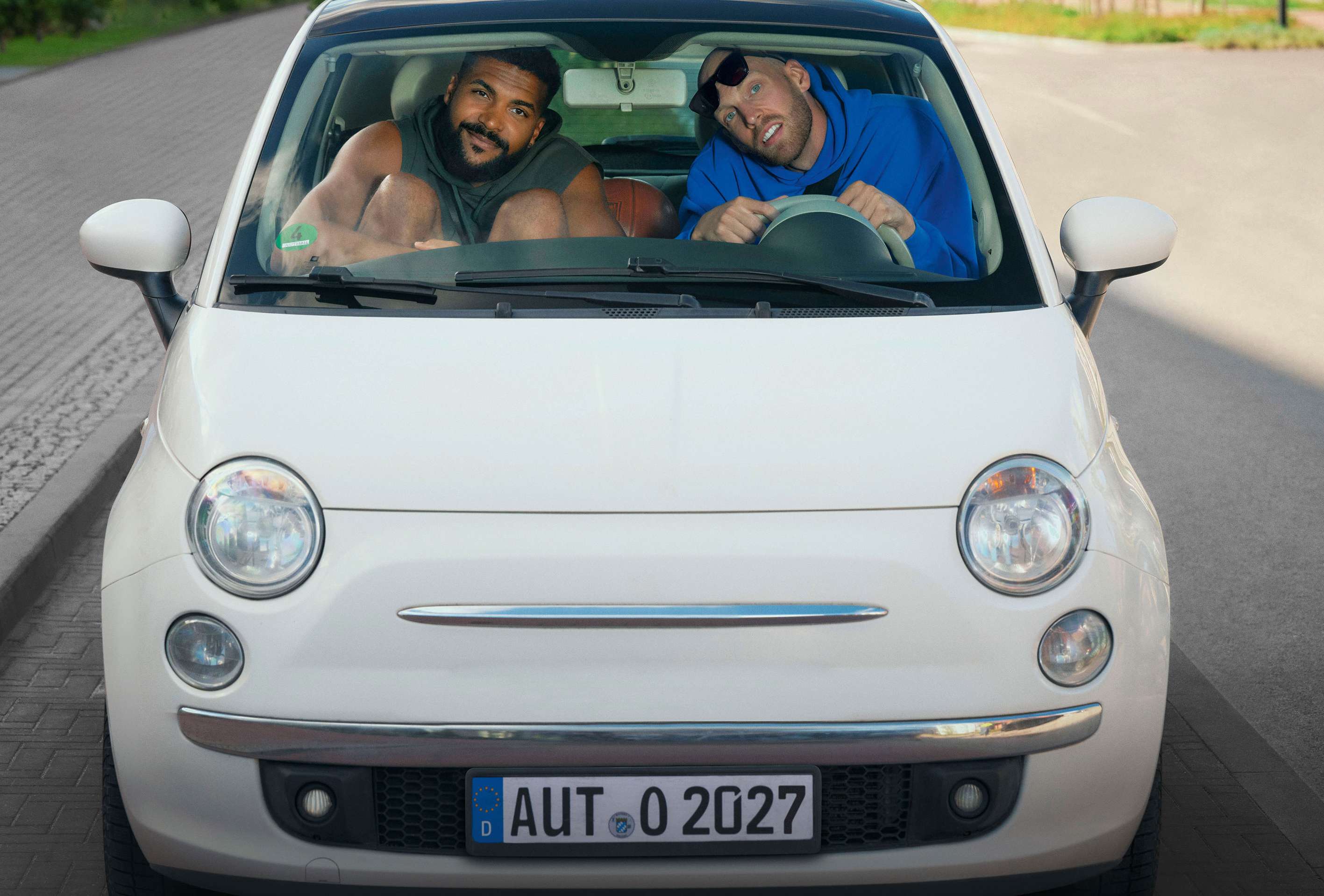 Schutzbrief: zwei sehr große Basketballprofis sitzen ein einem sehr kleinen Auto