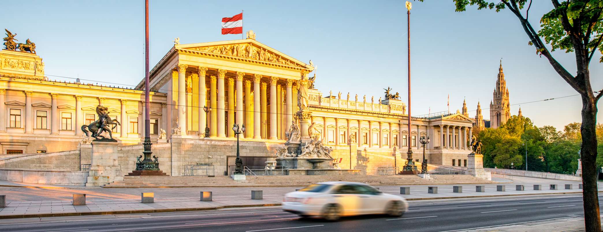 Weißes Auto fährt an Parlamentsgebäude in Österreichs Hauptstadt Wien vorbei 