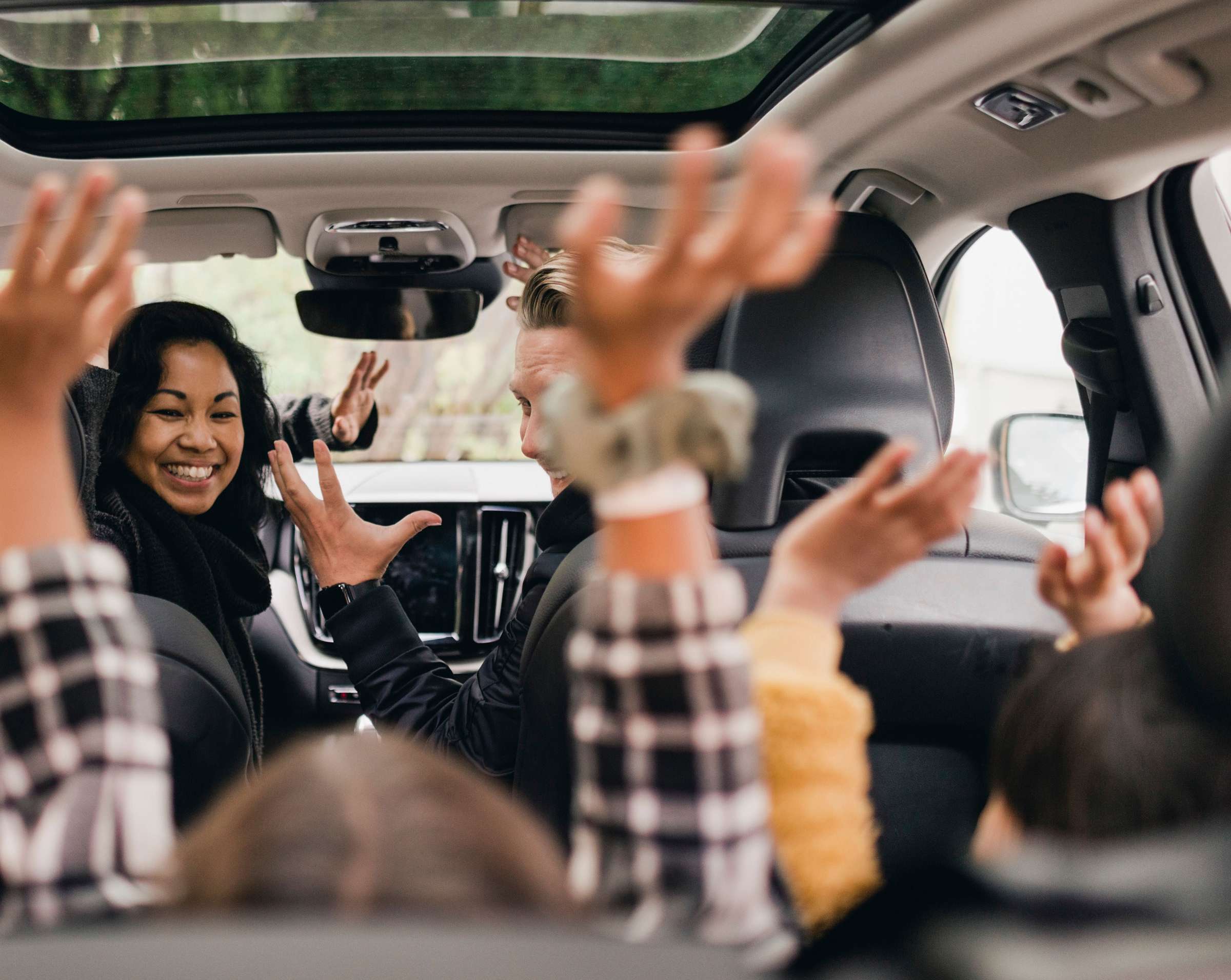 Vollkasko: Frau sitzt mit Kindern im Auto, die alle die Hände hochhalten.