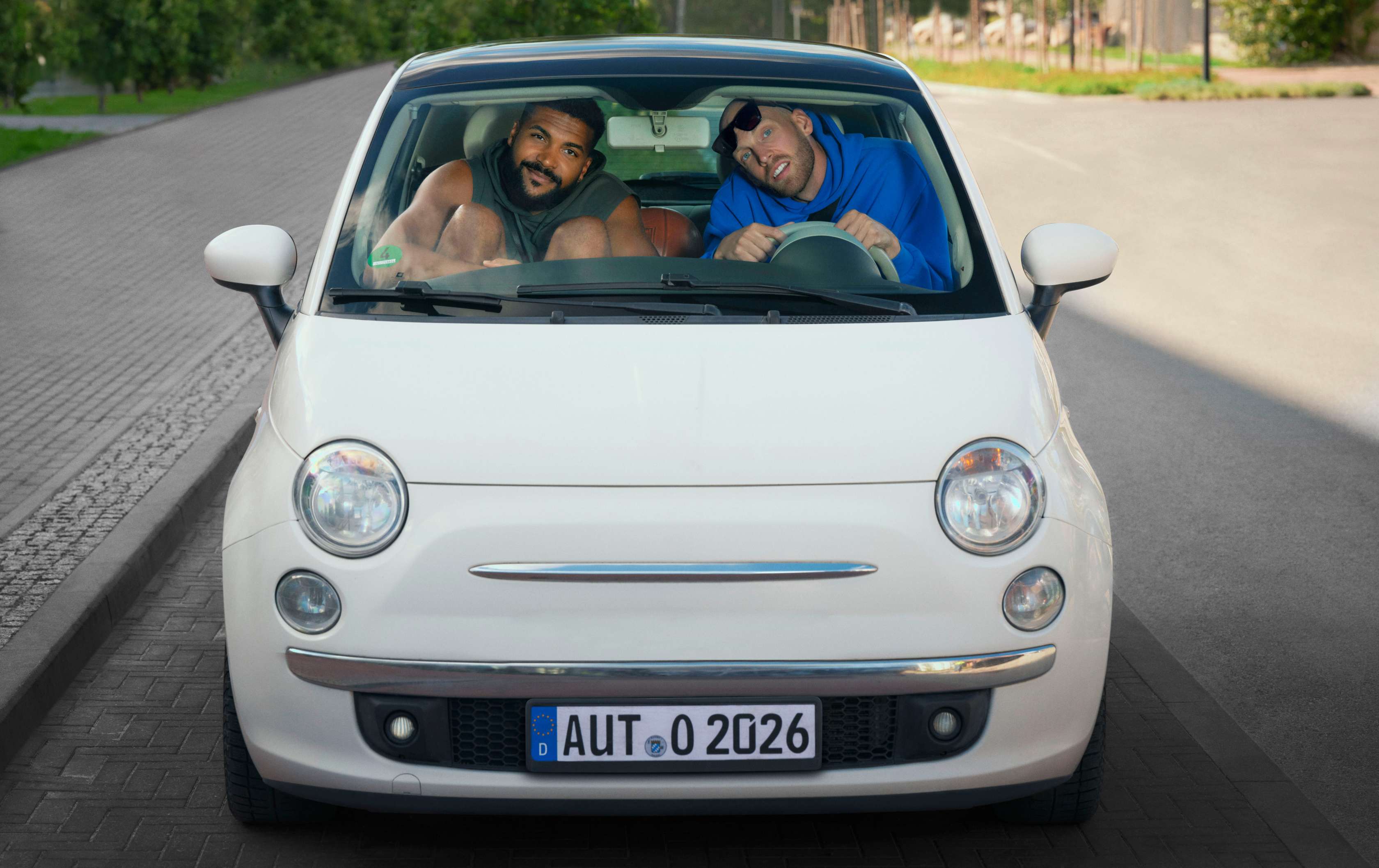 Kfz-Versicherung wechseln: zwei sehr große Basketballprofis sitzen ein einem sehr kleinen Auto