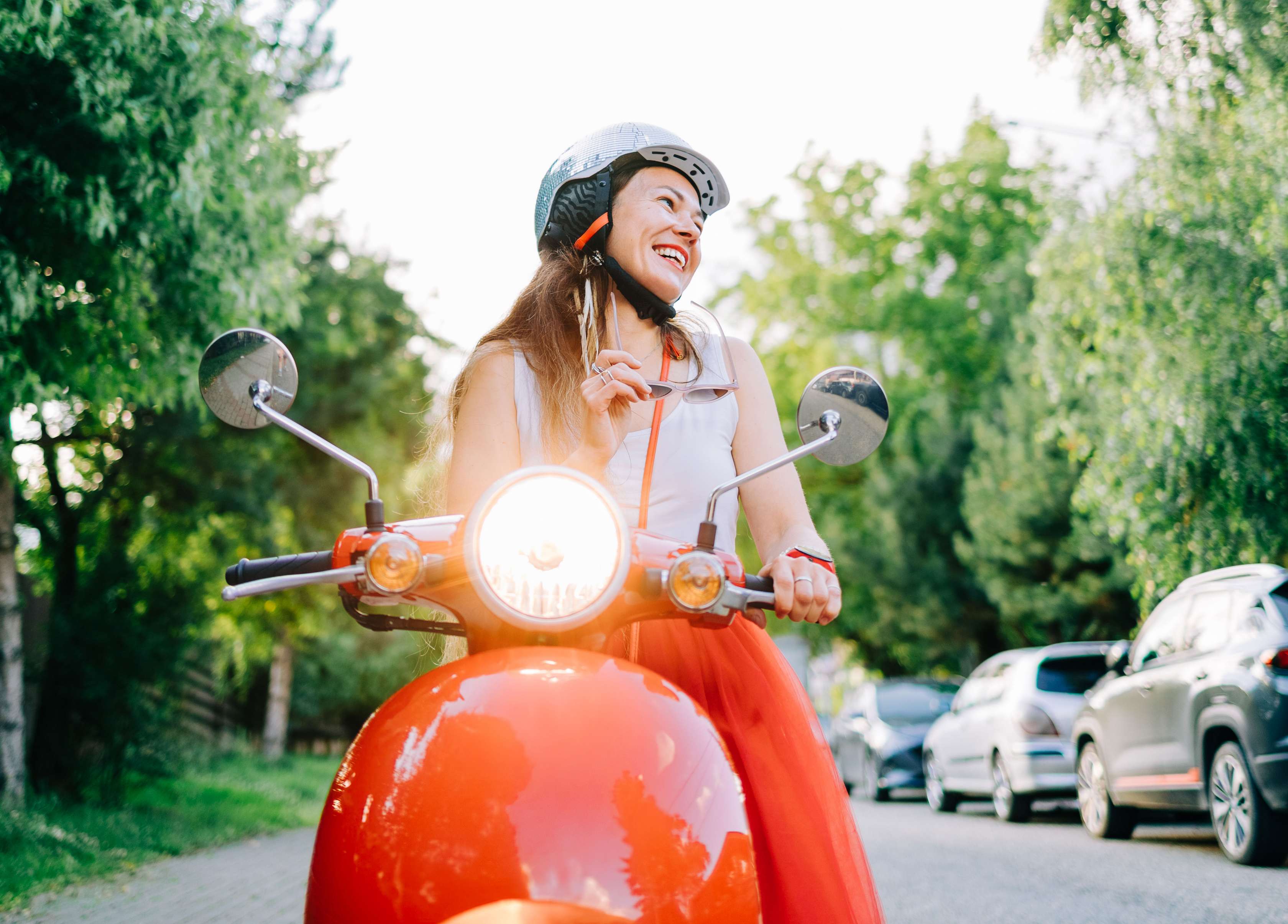 Rollerführerschein: Frau auf Roller fährt lachend duch einen Ort