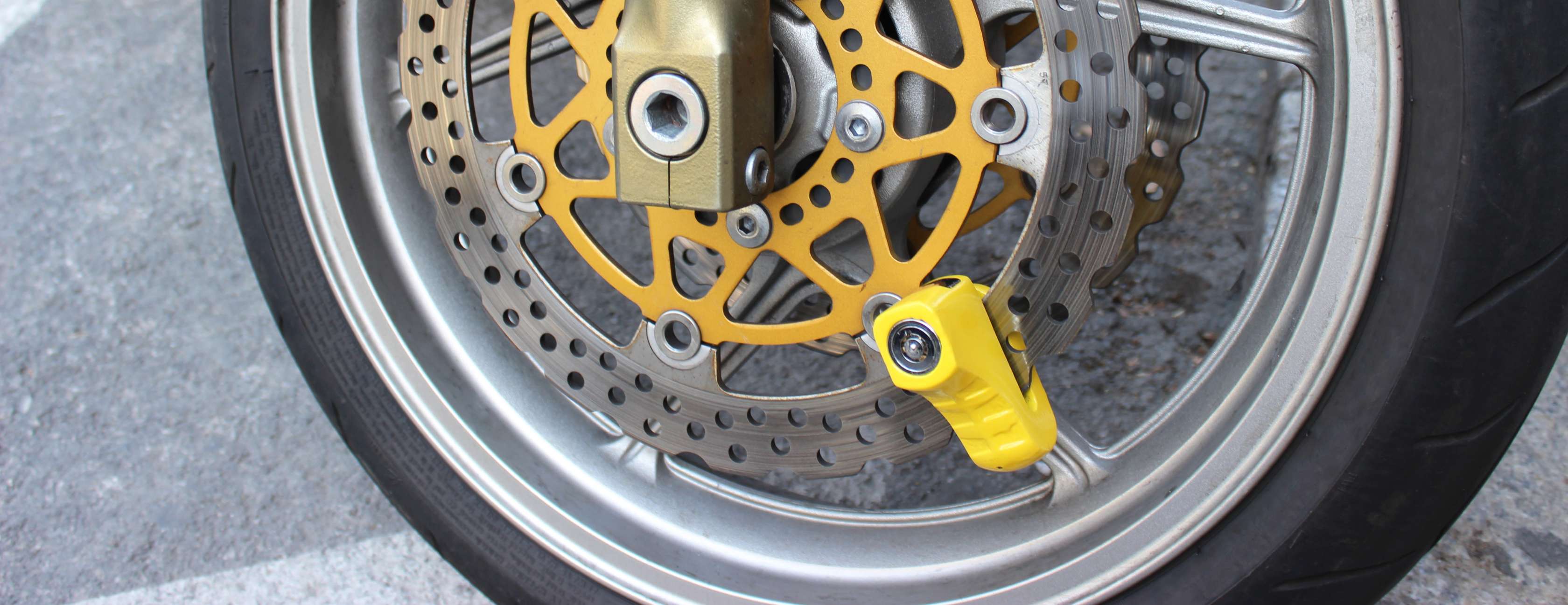 Allianz – Motorrad Diebstahlschutz: Motorradreifen mit einem gelben Bremsscheibenschloss