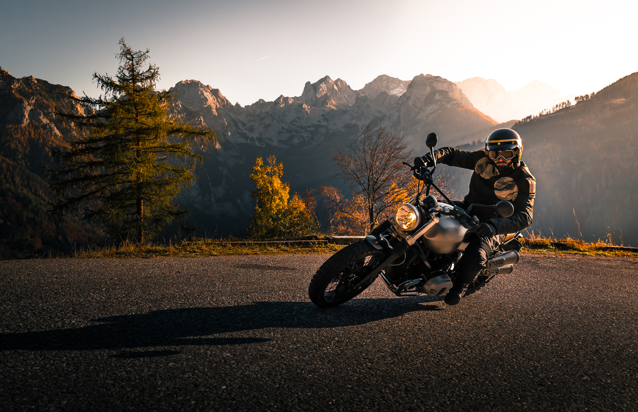 Motorradfahrer mit Helm und Schutzbrille legt sich beim Motorradfahren in eine Kurve
