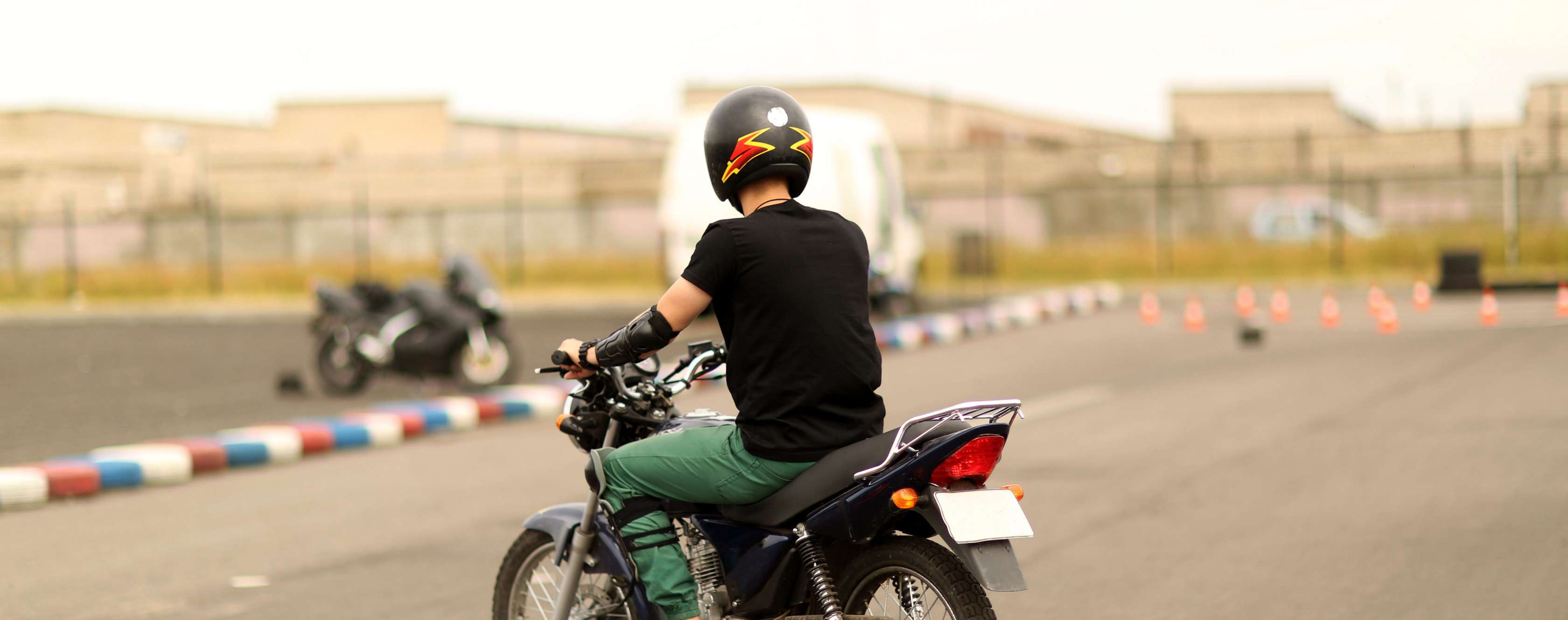 Motorradfahrer mit Helm fährt auf Übungsplatz einen Parkour ab