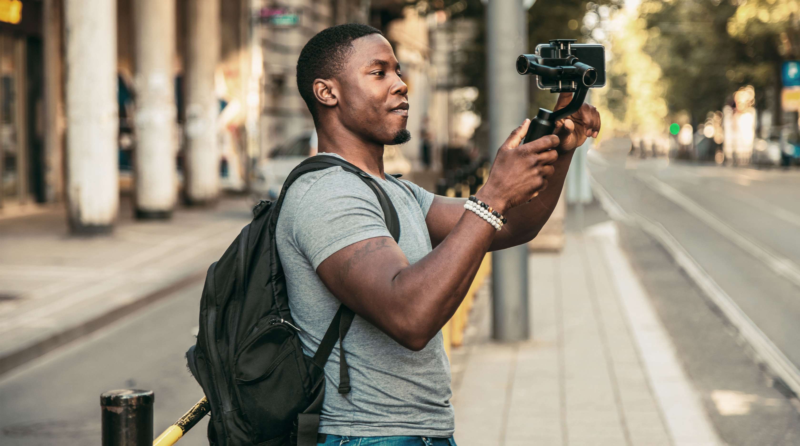 Man sieht einen jungen Mann in der Stadt, der sein Mobiltelefon auf einem Stativ trägt und offenbar sich selbst filmt.