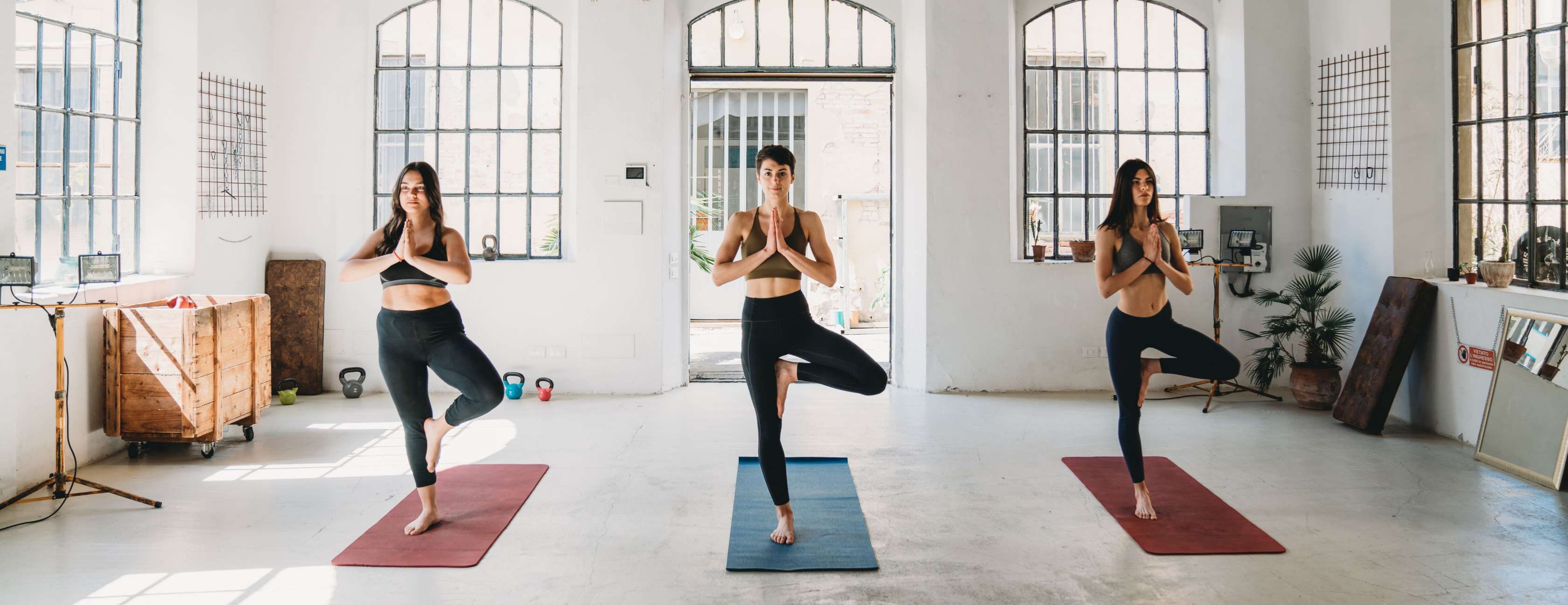 Drei Frauen machen Yoga-Übungen in einem Studio.
