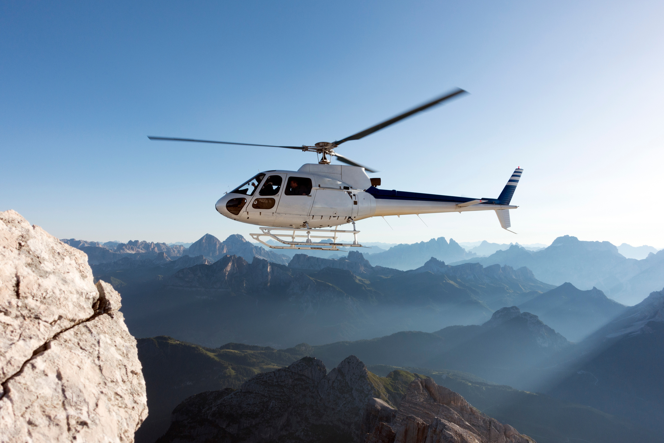 Ein Hubschrauber fliegt bei einem Einsatz über Berge.