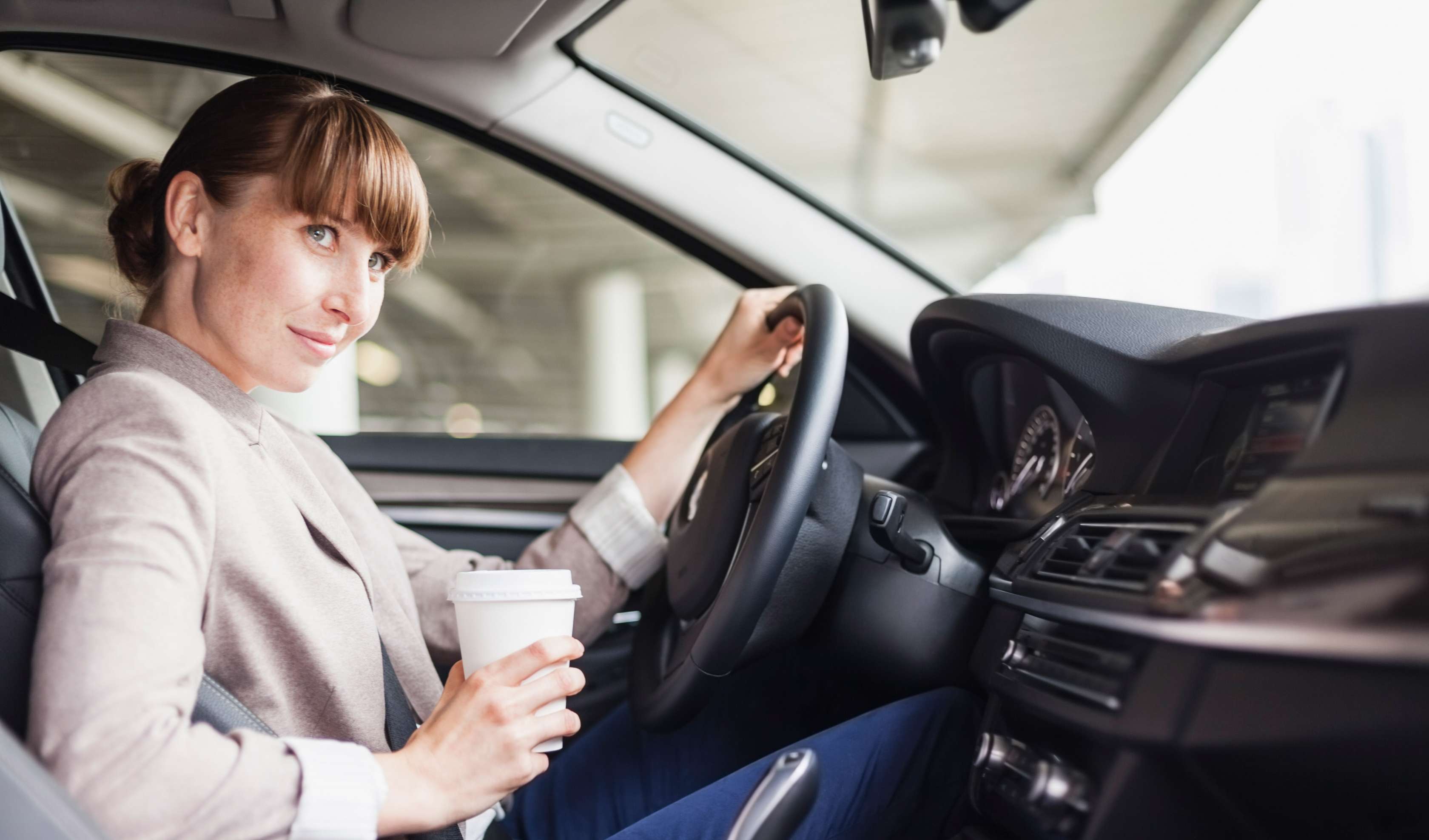 Eine Frau sitzt lächelnd am Steuer eines Autos