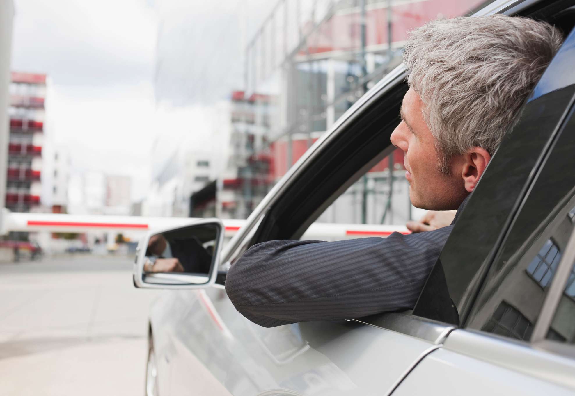 Allianz - KFZ-Haftpflichtversicherung: Mann im Anzug im Auto lehnt sich leicht aus dem Fenster