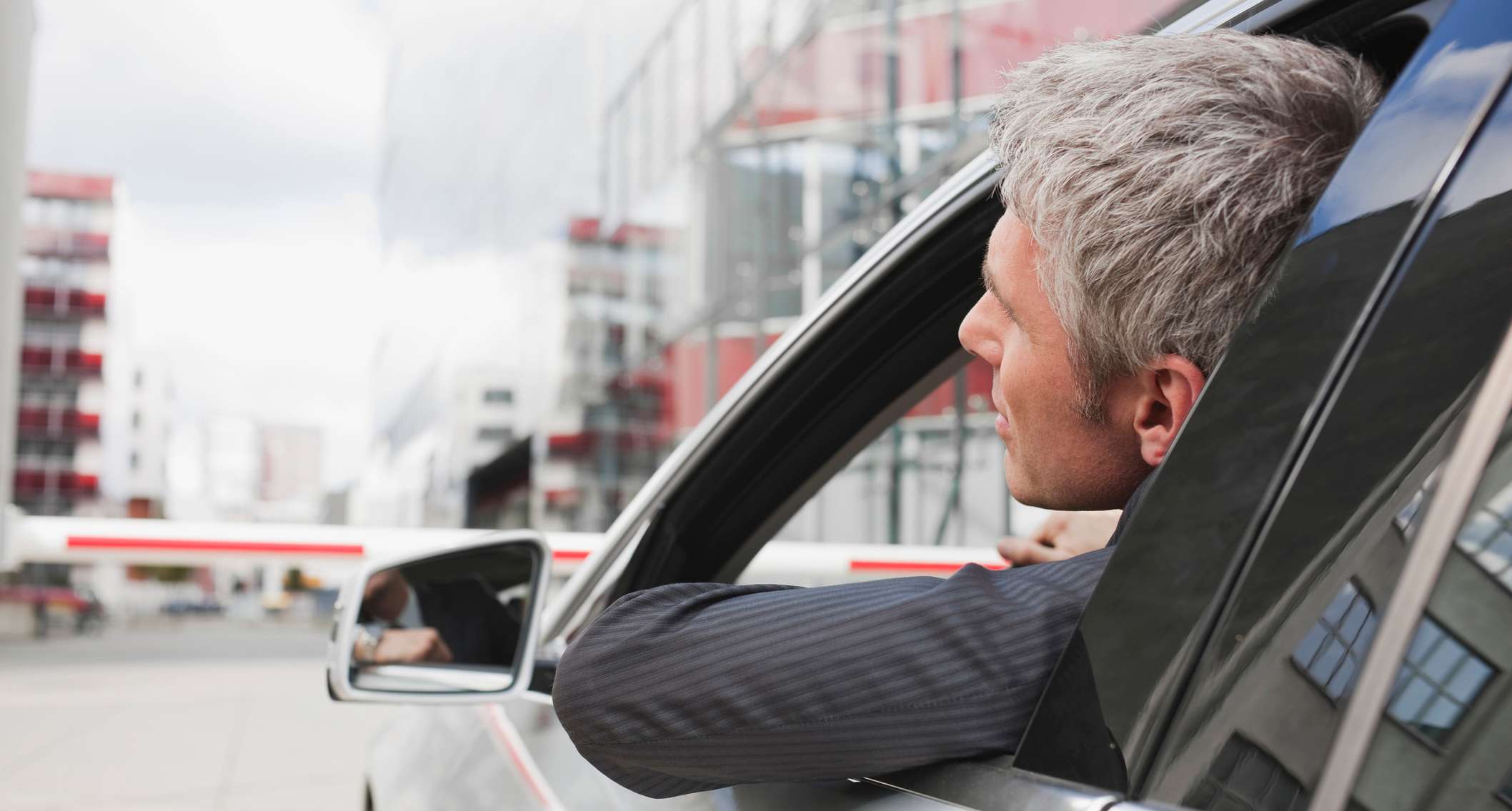 Allianz - KFZ-Haftpflichtversicherung: Mann im Anzug im Auto lehnt sich leicht aus dem Fenster