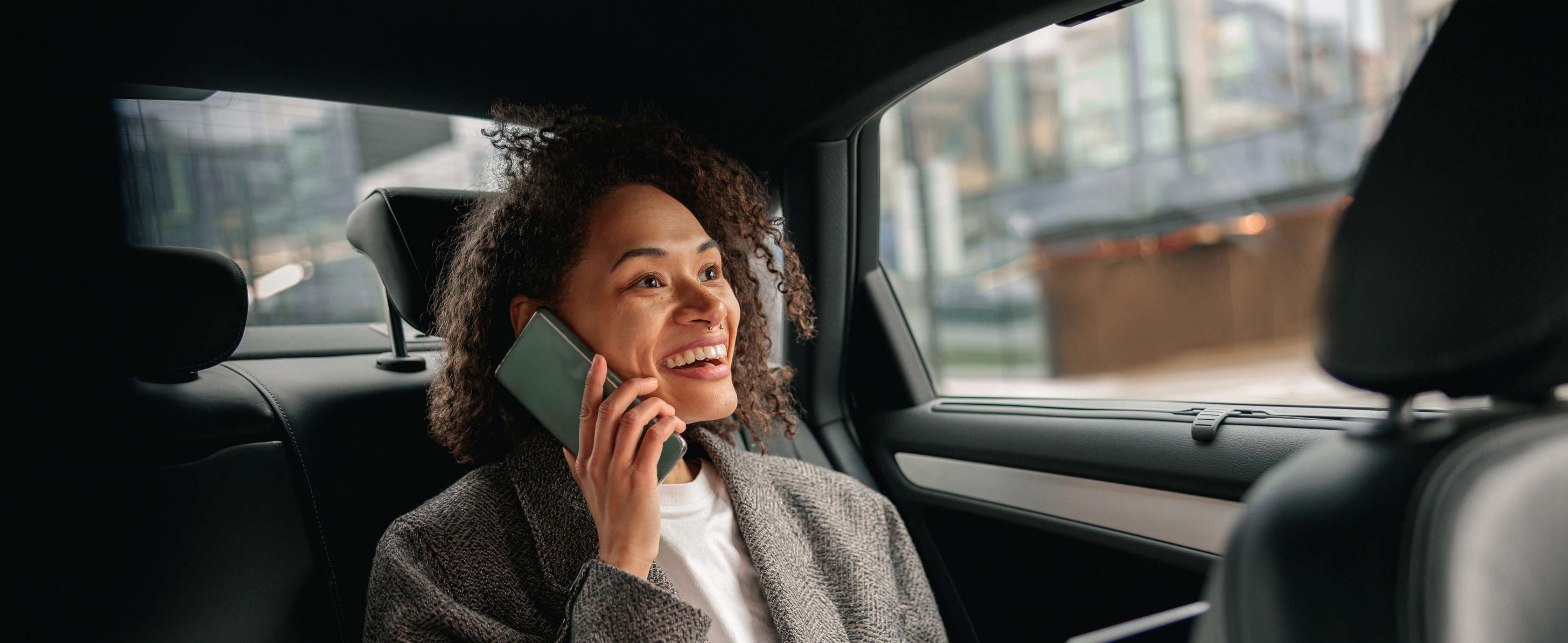 Allianz - KFZ-Vollkaskoversicherung: Mann sitzt hinten im Auto und telefoniert