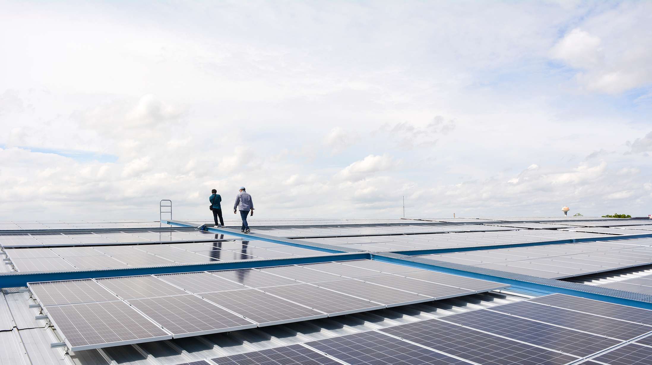 Zwei Männer gehen über ein Dach mit einer großen Photovoltaikanlage.