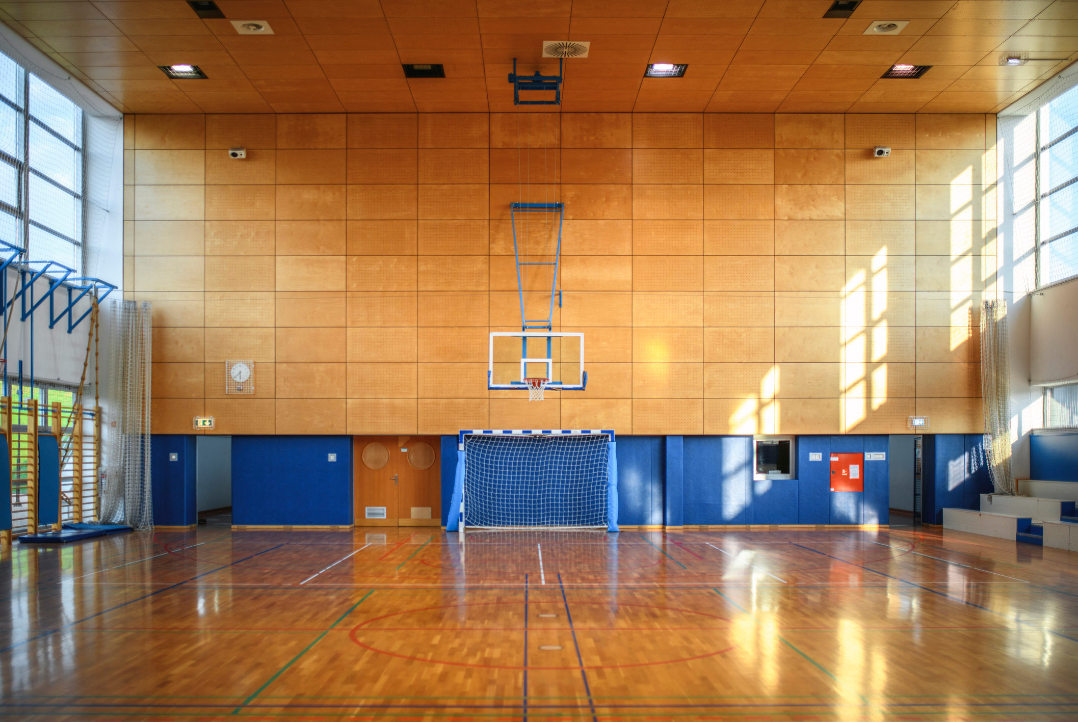 Eine große lichtdurchflutete Sporthalle mit einem Holzboden von innen fotografiert.
