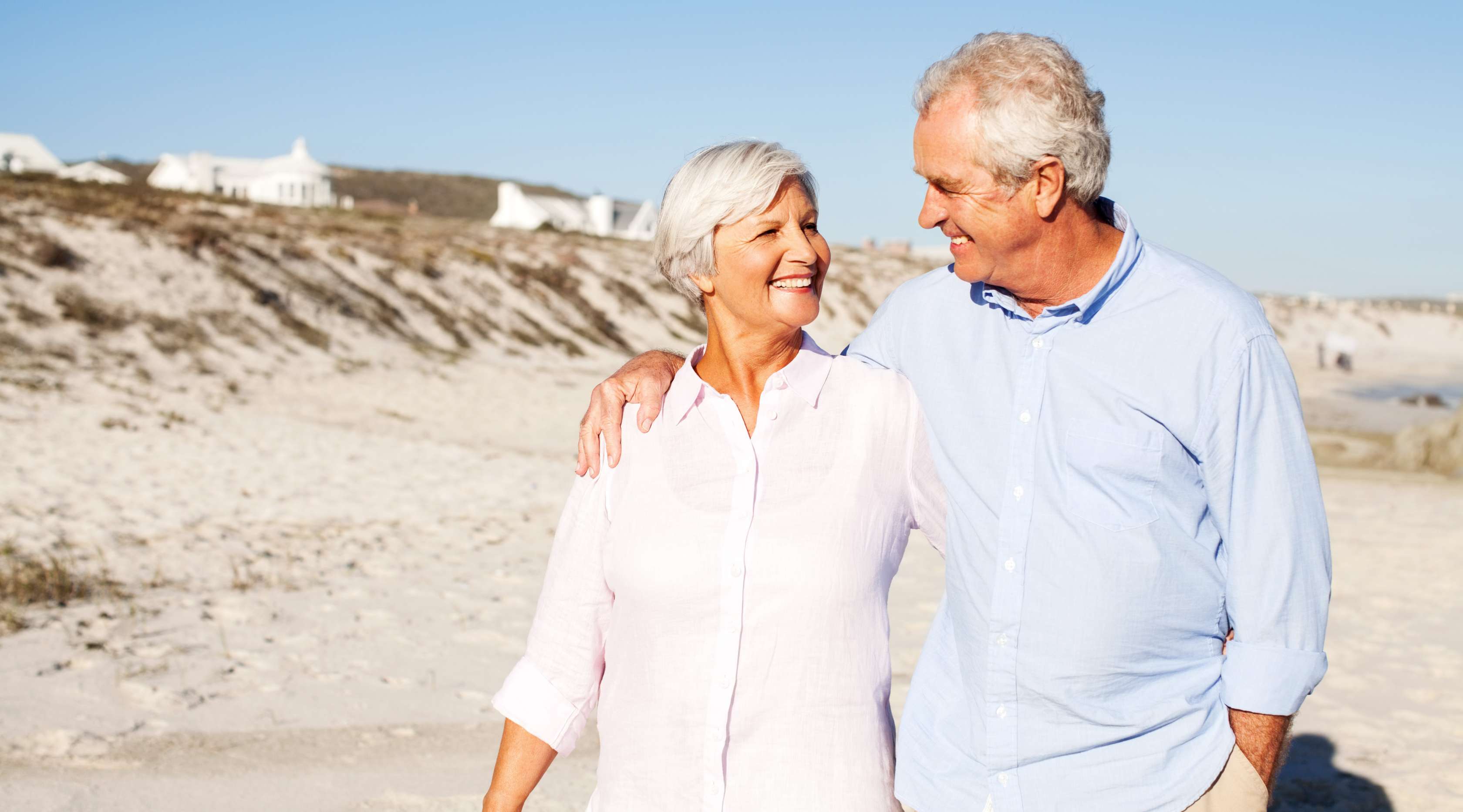 Allianz - Riester Rente: Älteres Paar spaziert glücklich am Strand